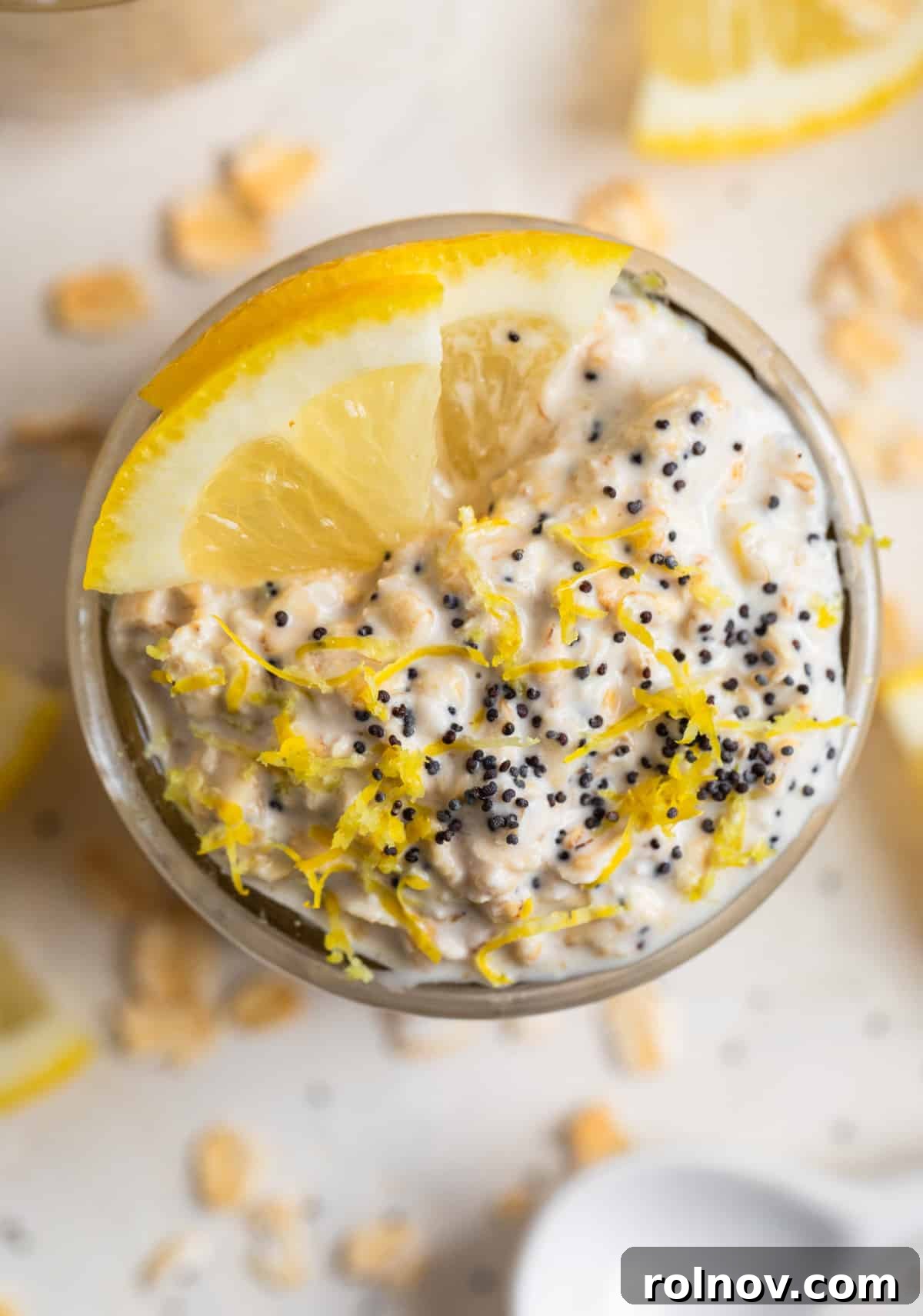 Sunshine Lemon Poppy Seed Overnight Oats 3 Overhead shot of lemon poppy seed overnight oats in a glass jar, garnished with a sprinkle of poppy seeds and a lemon slice.