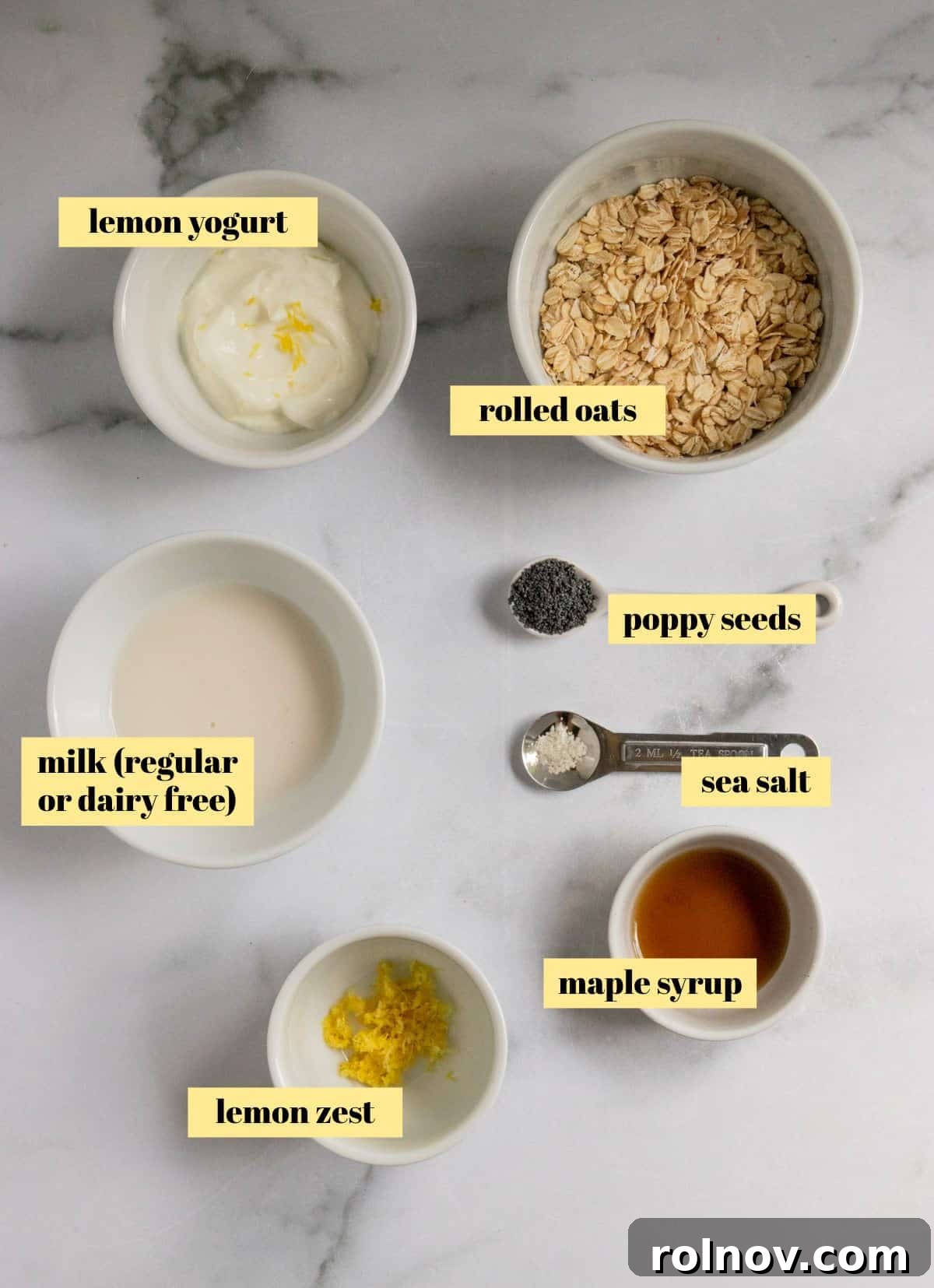 Sunshine Lemon Poppy Seed Overnight Oats 4 Various ingredients for lemon poppy seed overnight oats laid out on a surface: oats, milk, lemon yogurt, poppy seeds, lemon, and maple syrup.