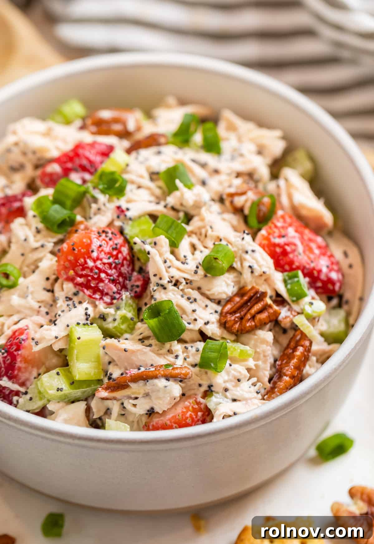 Berry Bliss Chicken Salad with Poppy Seed Pecans 2 A beautifully presented ceramic bowl filled with Strawberry Pecan Chicken Salad, garnished with fresh strawberries, pecans, and green onion slices.