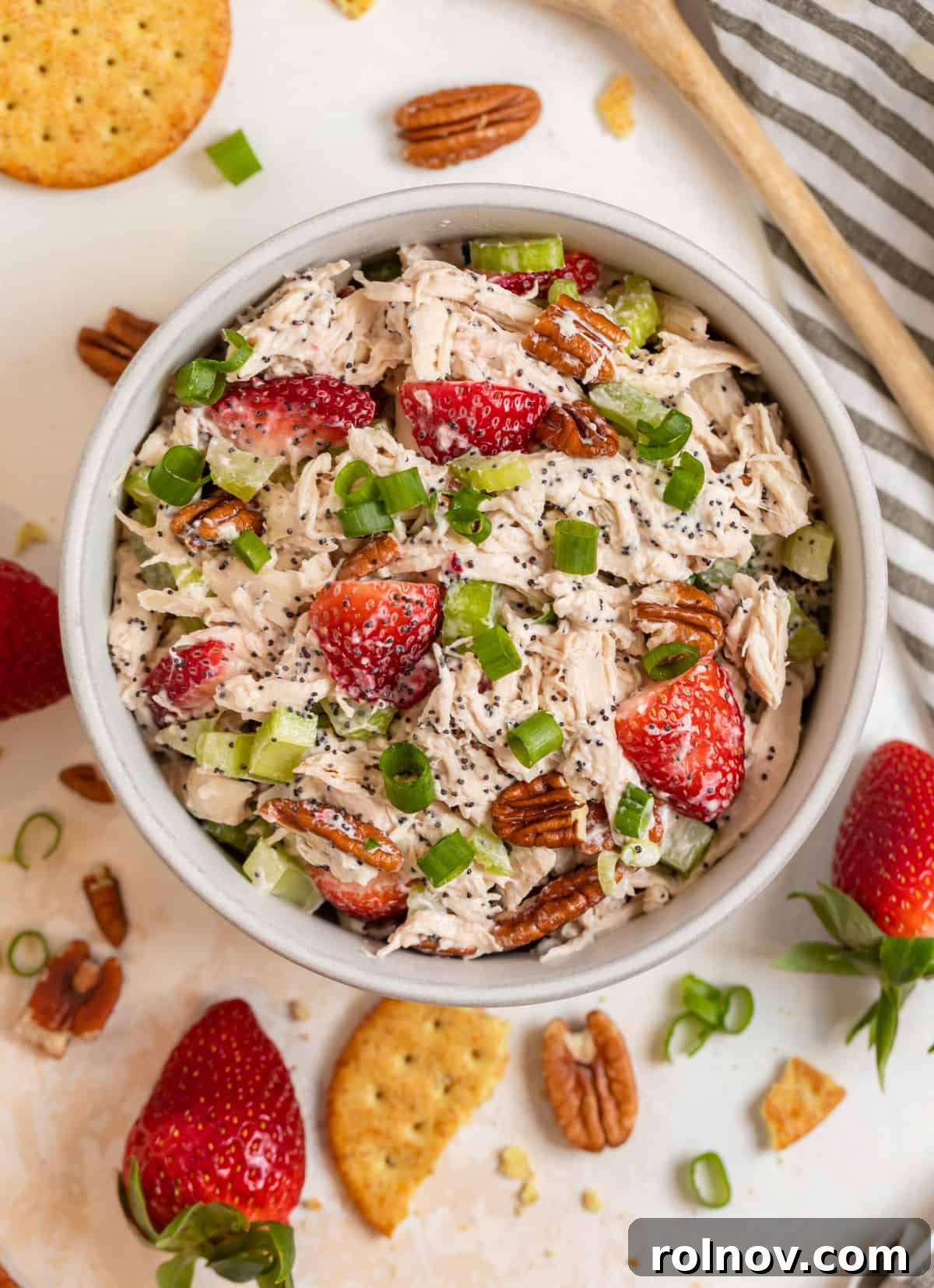 Berry Bliss Chicken Salad with Poppy Seed Pecans 3 A cozy scene featuring Strawberry Pecan Poppy Seed Chicken Salad served in a bowl, surrounded by fresh strawberries and crunchy crackers, ready for enjoyment.