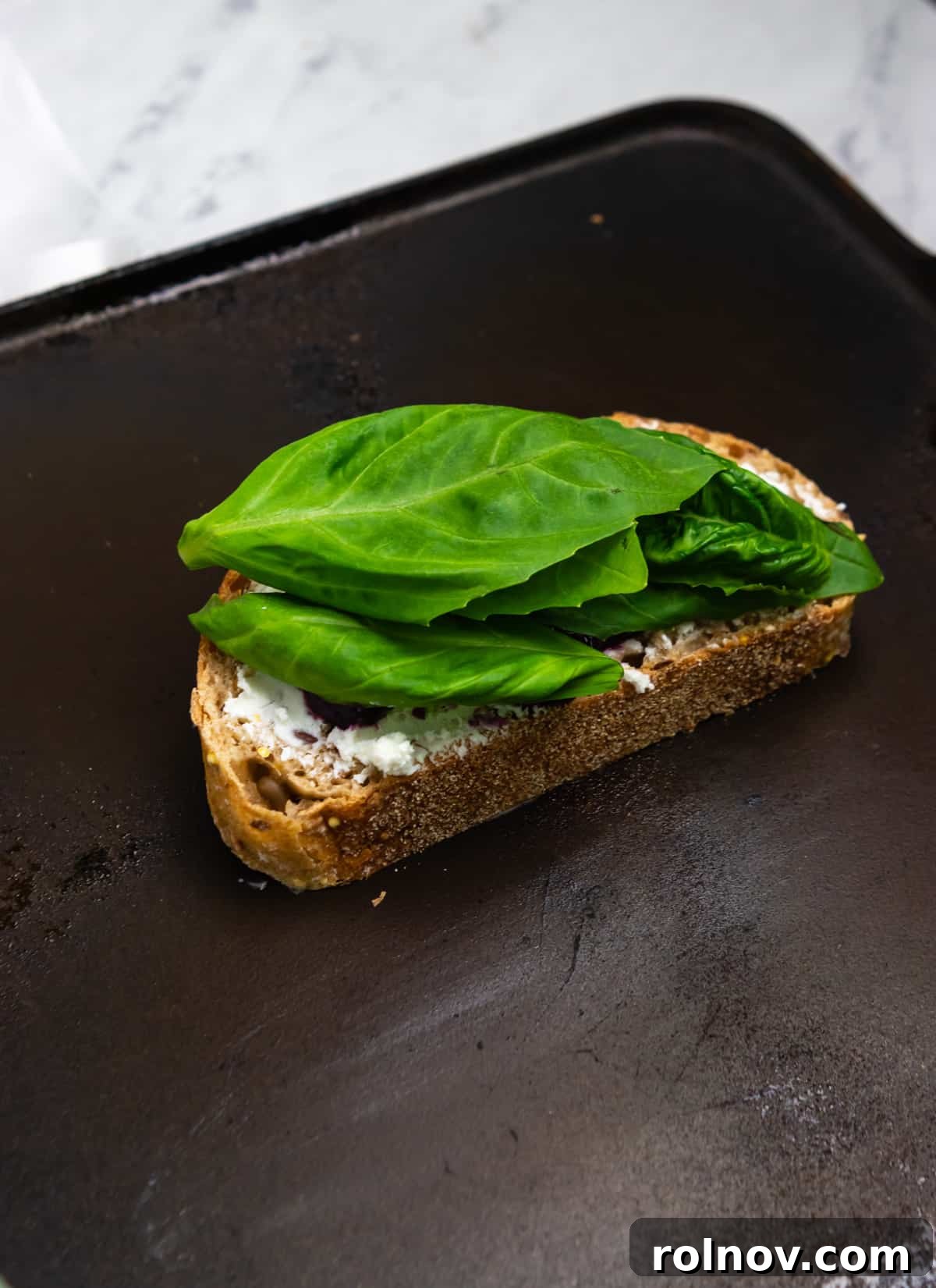 Sweet & Savory Blueberry Basil Goat Cheese Grill 6 Grilled cheese sandwich with fresh basil leaves on top, sizzling gently in a cast iron skillet on a stovetop, ready to be served.