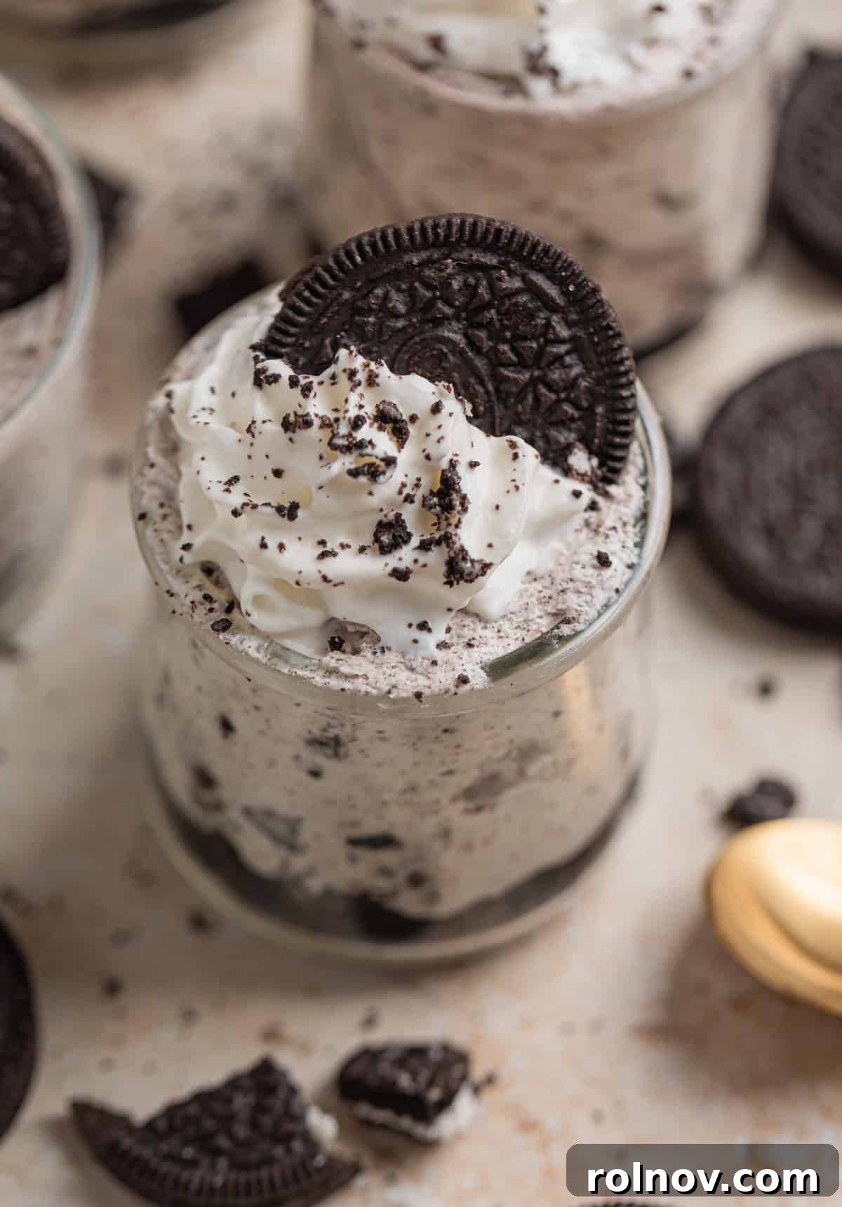 Effortless Oreo Cheesecake Treats 2 Vibrant No-Bake Oreo cheesecake cup topped generously with whipped cream and crushed Oreo cookies, ready to be enjoyed.
