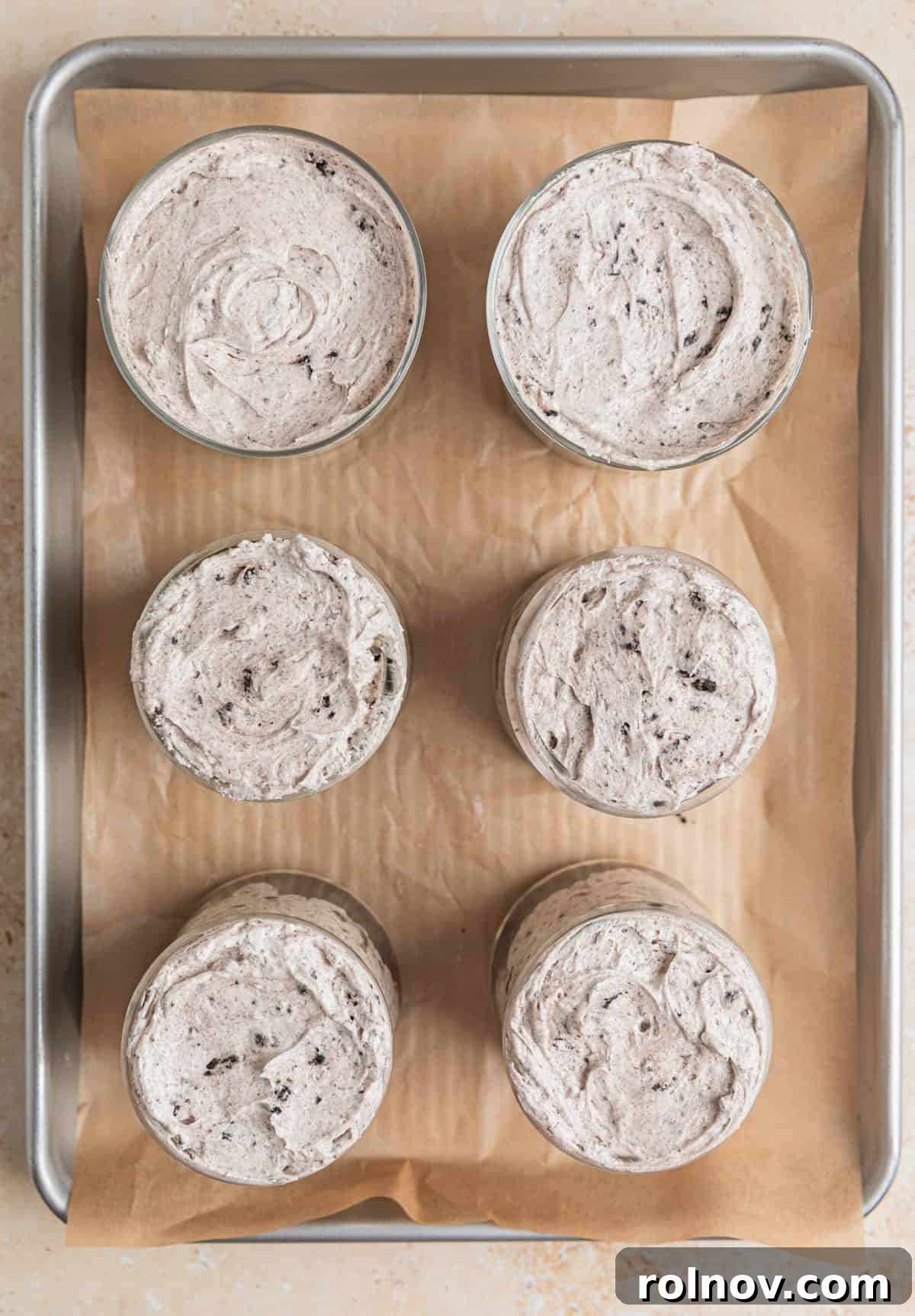 Effortless Oreo Cheesecake Treats 12 Individual glass dessert dishes neatly filled with the creamy no-bake Oreo cheesecake mixture, ready for chilling.