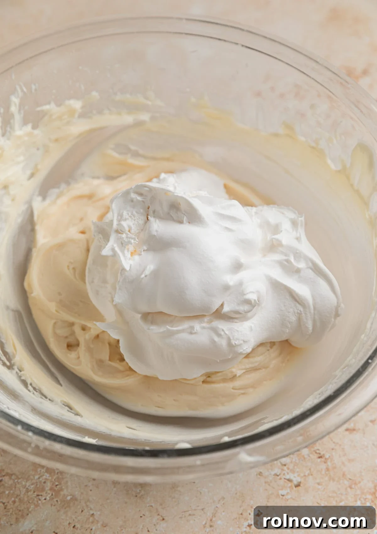 Effortless Oreo Cheesecake Treats 8 Cool Whip being added to the cream cheese and powdered sugar mixture in a bowl, prior to folding.