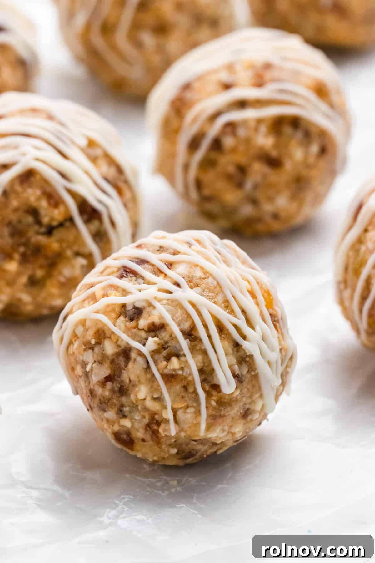 Vibrant No-Bake Mango Coconut Cashew Bars drizzled with white chocolate, on parchment paper.