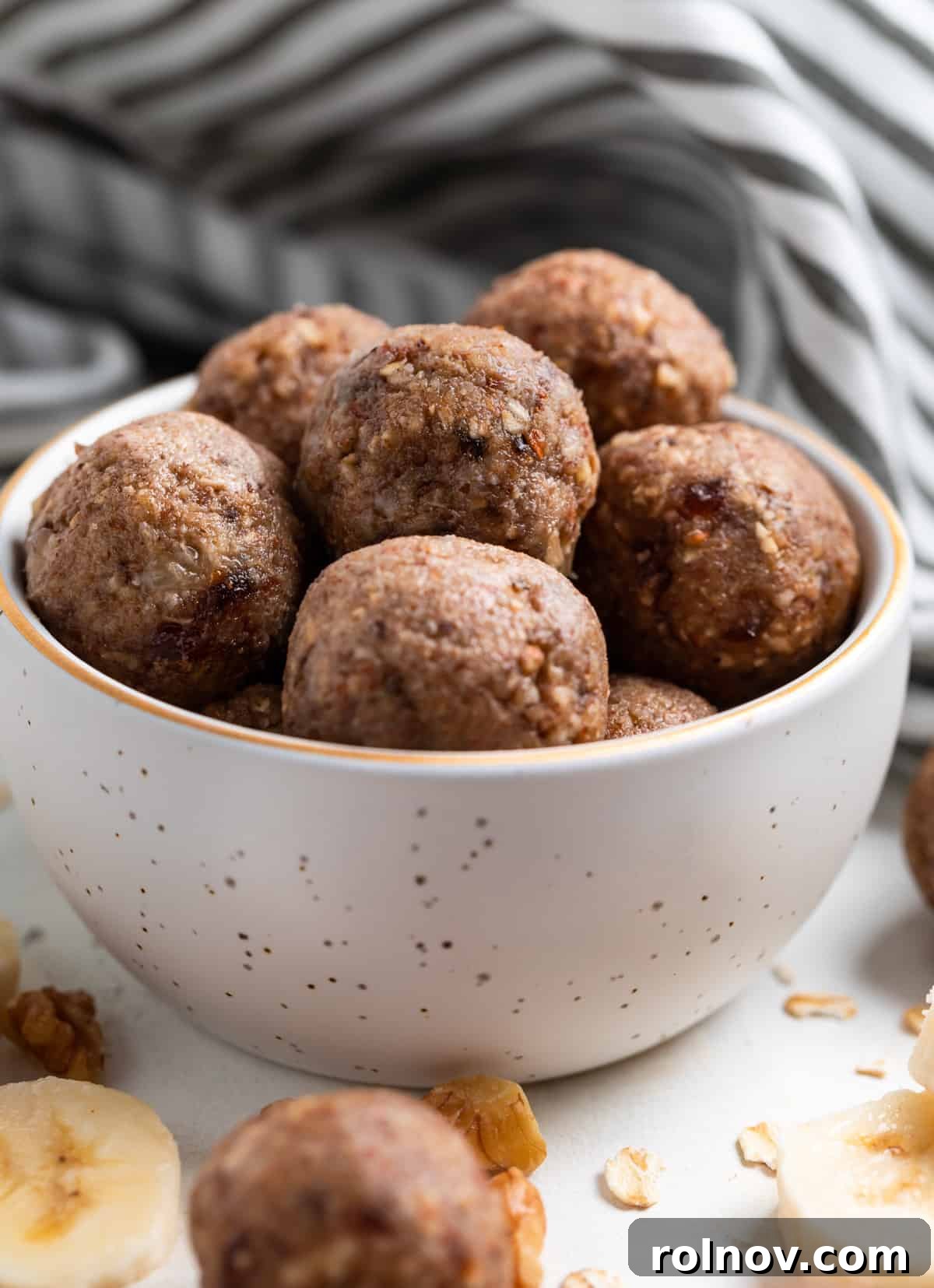 Banana oat balls in bowl with linen behind.