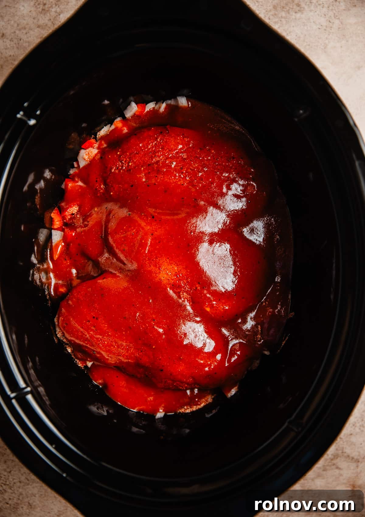 Effortless Slow Cooker BBQ Pulled Chicken 5 BBQ sauce poured over chicken in a slow cooker, ready for cooking.