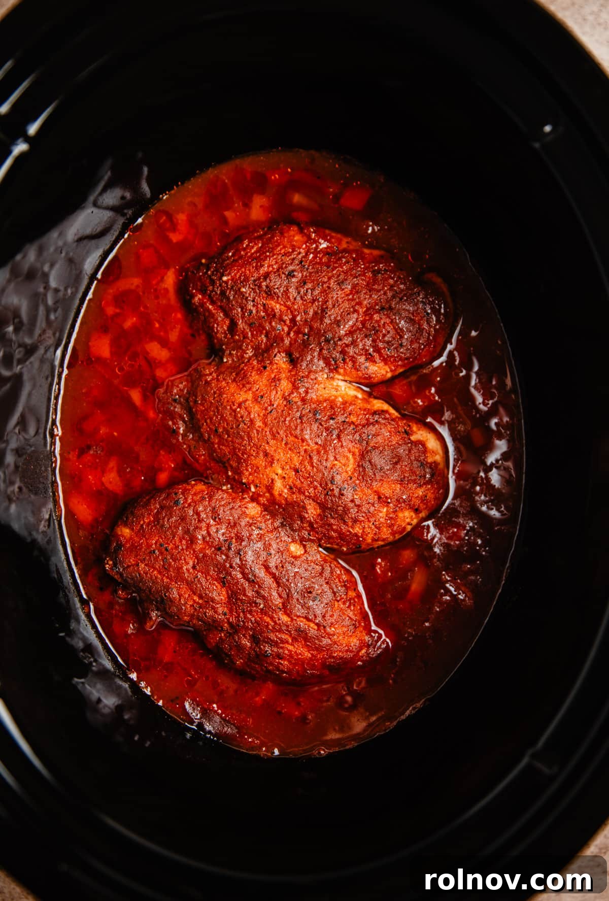 Effortless Slow Cooker BBQ Pulled Chicken 6 Fully cooked BBQ chicken in a slow cooker, still in whole pieces before shredding.