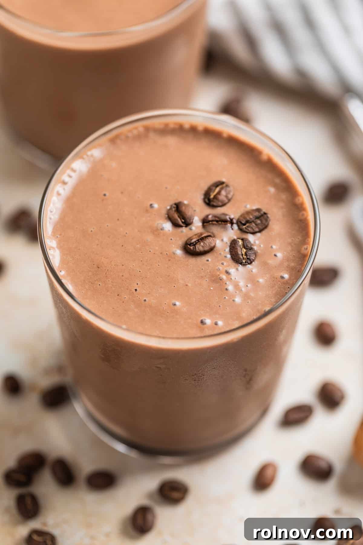 Peanut butter coffee smoothie in glass topped with coffee beans.