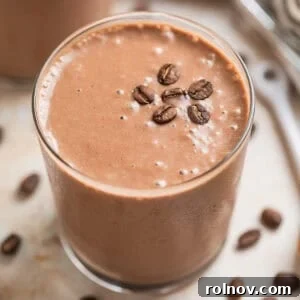 Peanut butter coffee smoothie in glass with coffee beans on top.