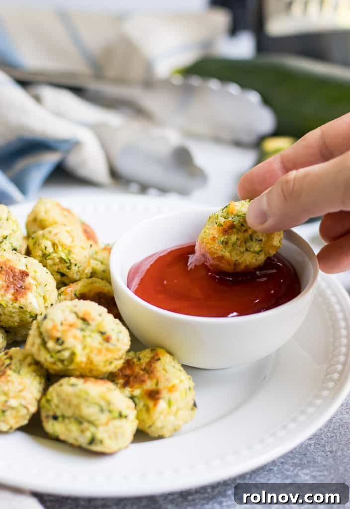 Zucchini Cheese Poppers 6 Smiling baby enjoying Cheesy Zucchini Tots, emphasizing kid-friendly healthy recipes.