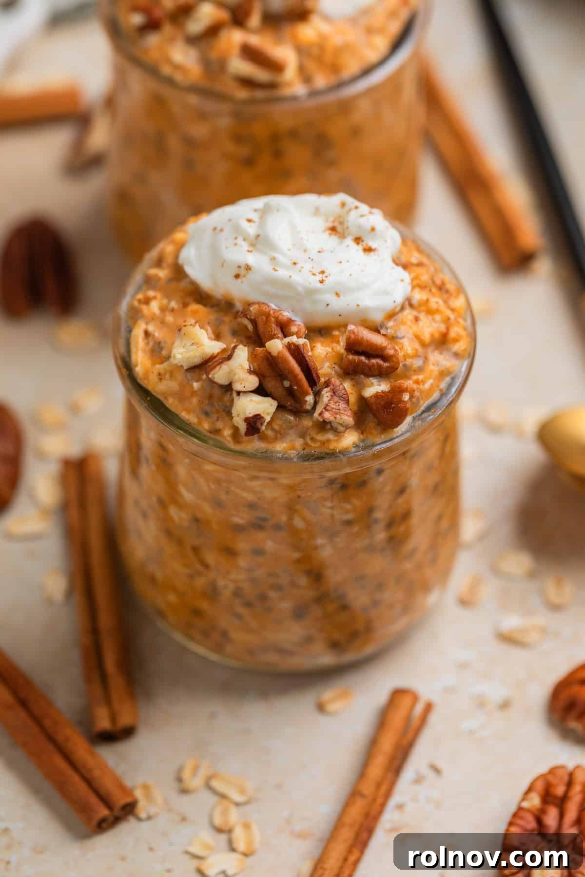 Spiced Pumpkin Overnight Oats 2 Glass jar with pumpkin pie overnight oats topped with whipped cream and chopped pecans.
