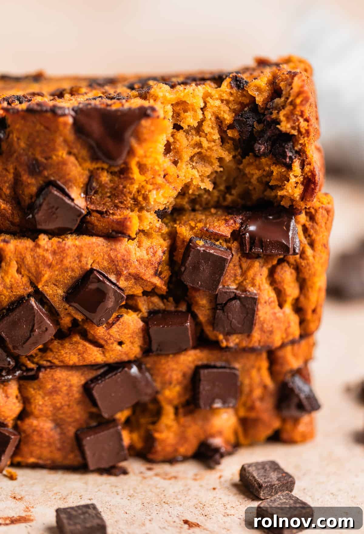 Pumpkin Speckled Banana Bread 2 Sliced pumpkin chocolate chip banana bread on counter with dark chocolate chunks surrounding.