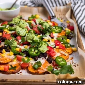 Sheet pan with sweet potato nachos covered with corn, beans, jalapeño, cheese, cilantro and avocado crema.