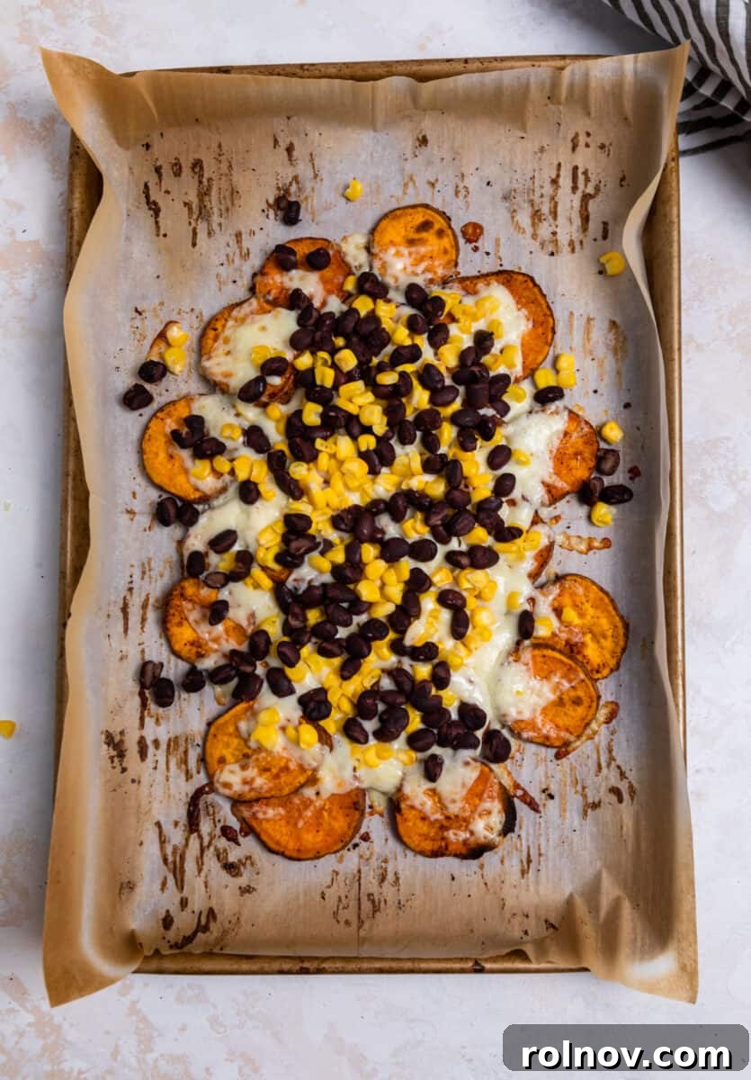 Melted cheese, cooked beans, and corn bubbling on roasted sweet potatoes after broiling.
