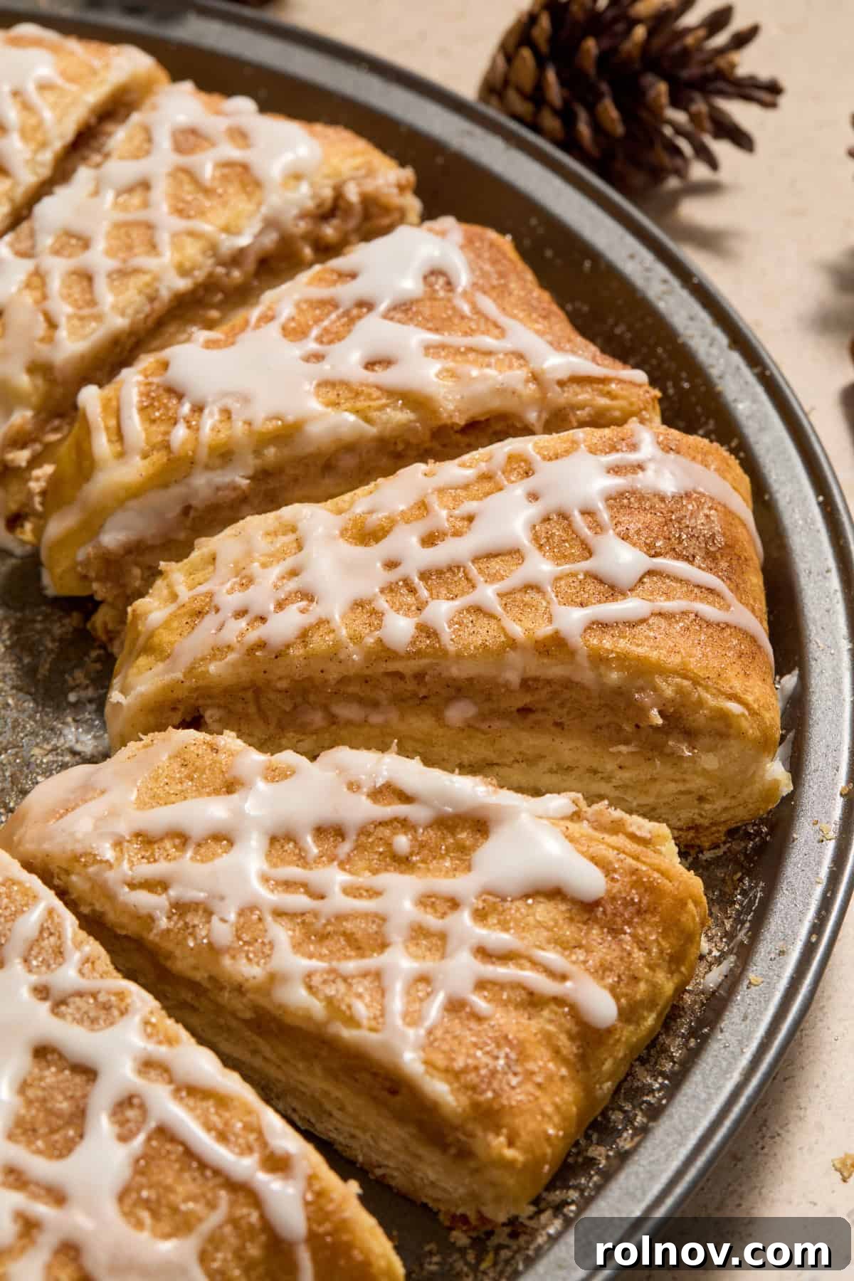 Slices of crescent roll wreath on pan with icing drizzle and cinnamon cream cheese filling.