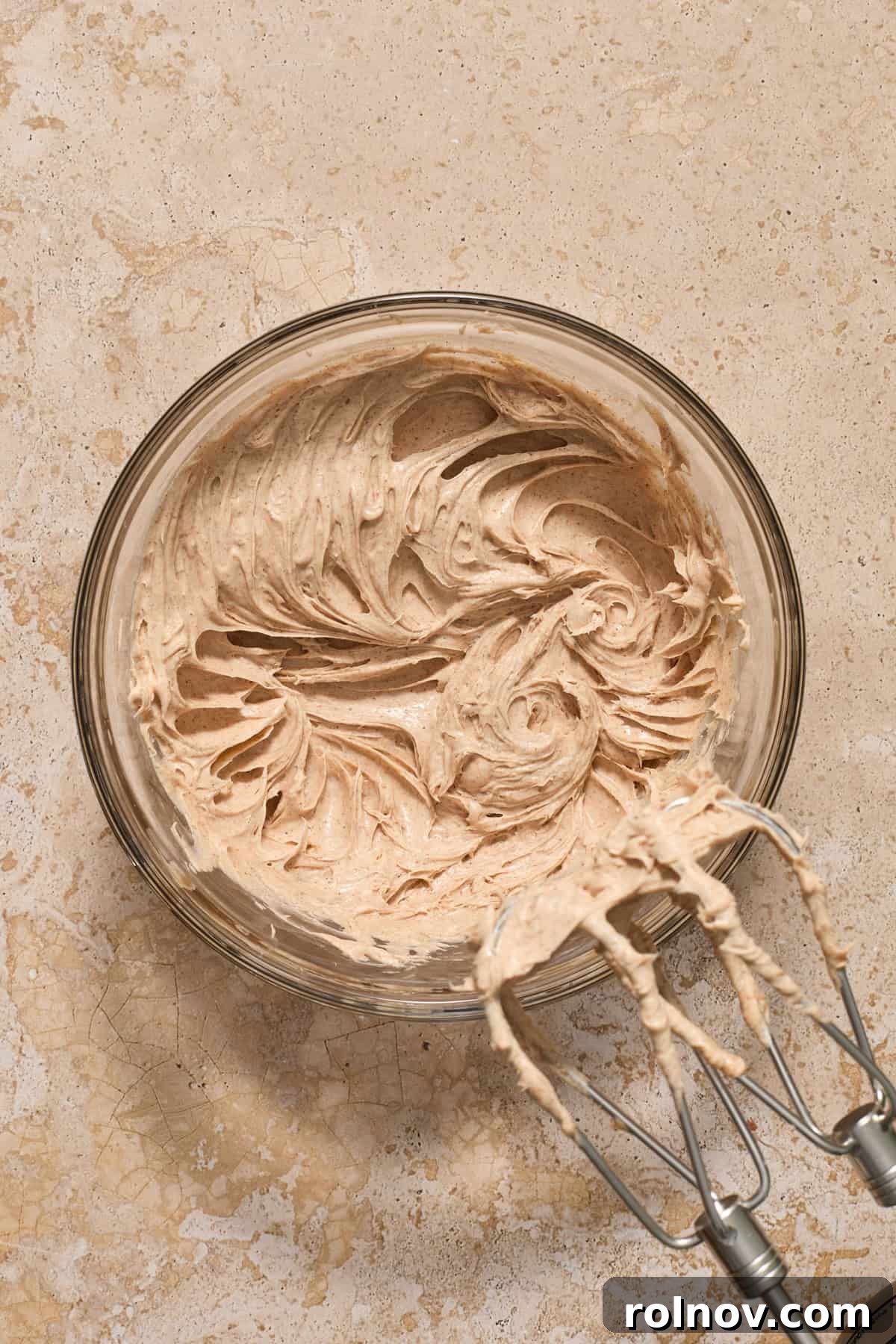 Creamed cream cheese and sugar in bowl with electric mixer propped to the side.