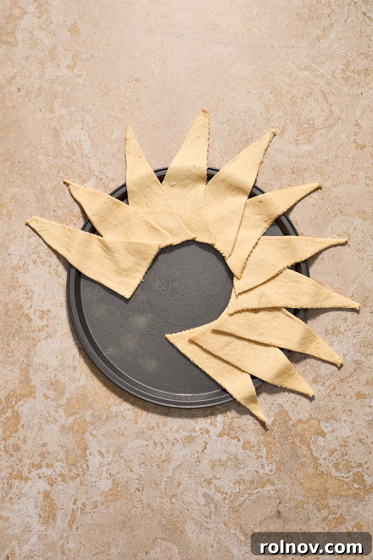 Crescent dough lined over halfway around a pizza pan to form a circular wreath shape.