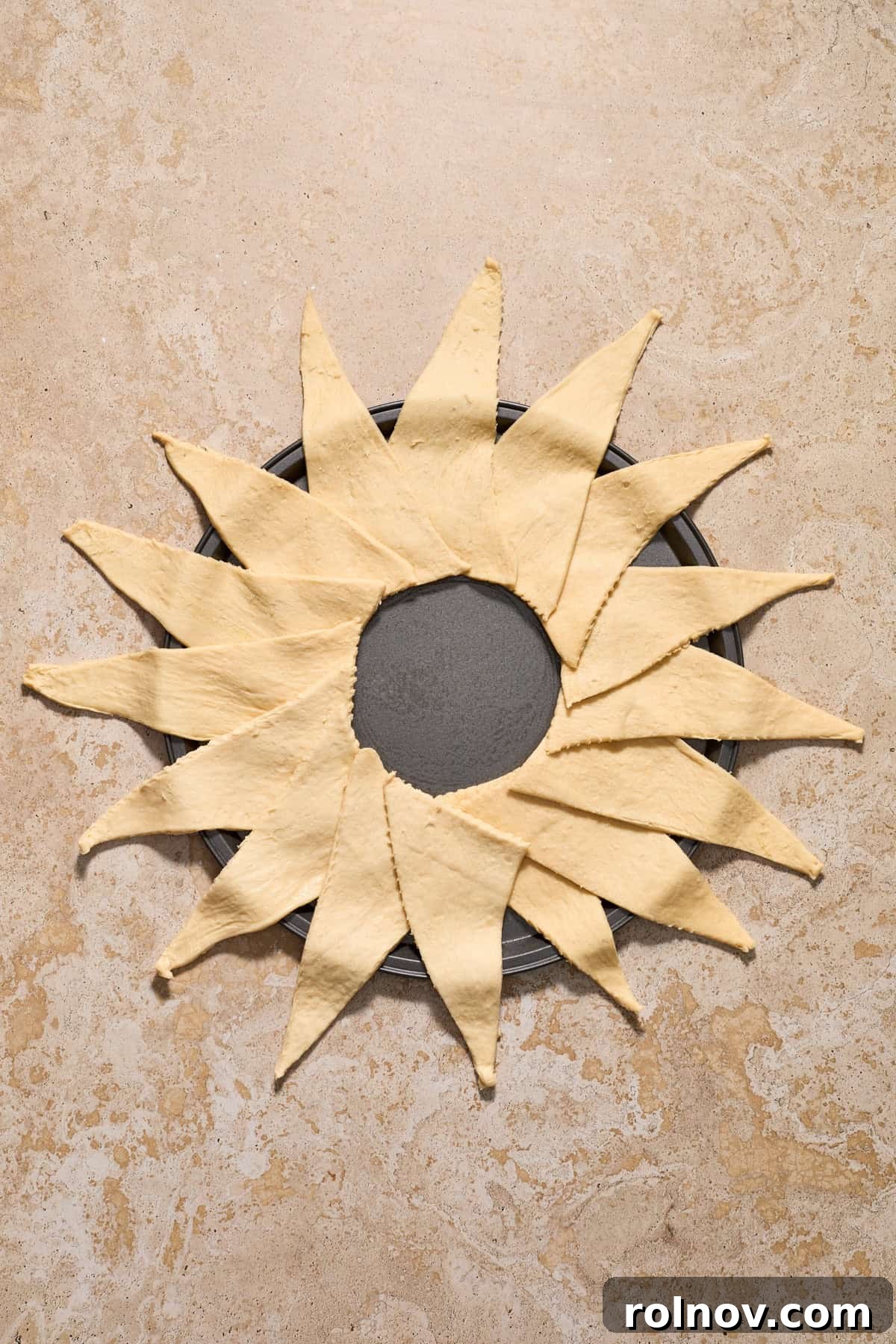 Crescent roll triangles arranged around a circular pan to form a full circle.