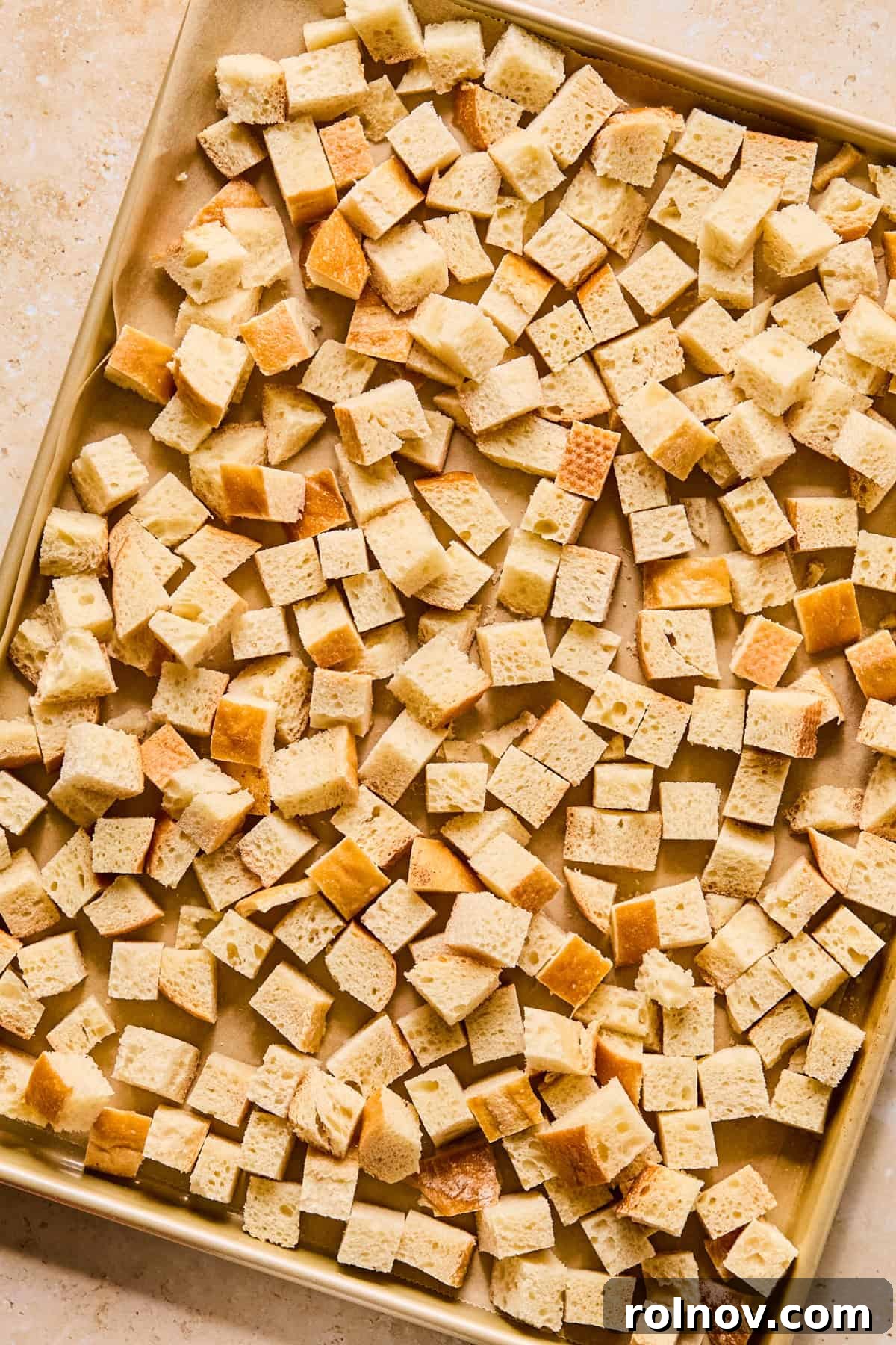 Homestyle Apple Sage Stuffing 5 Cubed stale bread spread evenly on a baking sheet, ready for drying.
