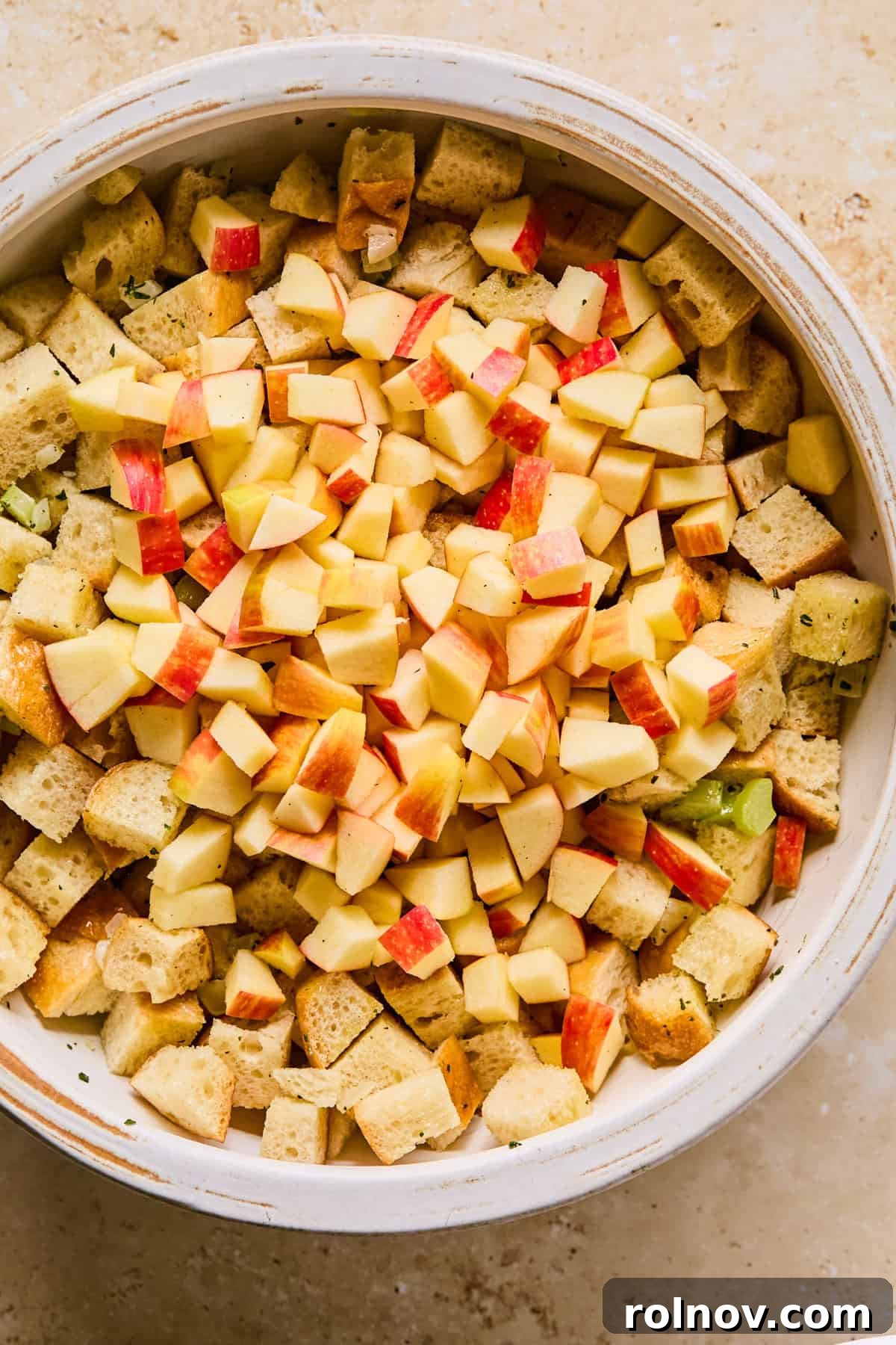 Homestyle Apple Sage Stuffing 7 Sautéed celery and onion mixture added to a large mixing bowl with bread cubes and chopped apples.