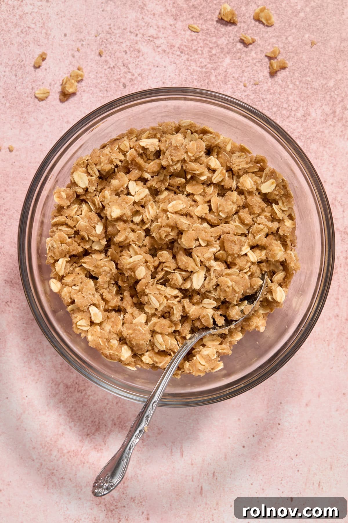 Oat crisp topping mixture in bowl with spoon.