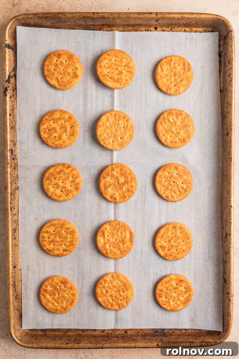 Ritz crackers arranged on parchment paper lined cooke sheet.