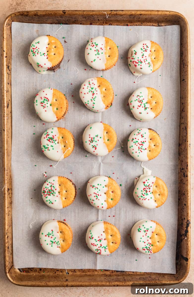 White chocolate dipped cracker sandwich cookies with red and green sprinkles on top.