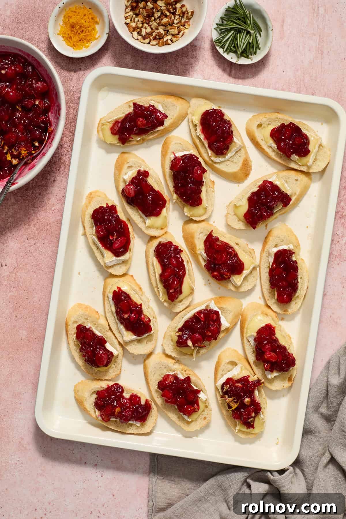 A close-up shot of a crostini with melted brie, generously topped with a spoonful of vibrant cranberry chutney.