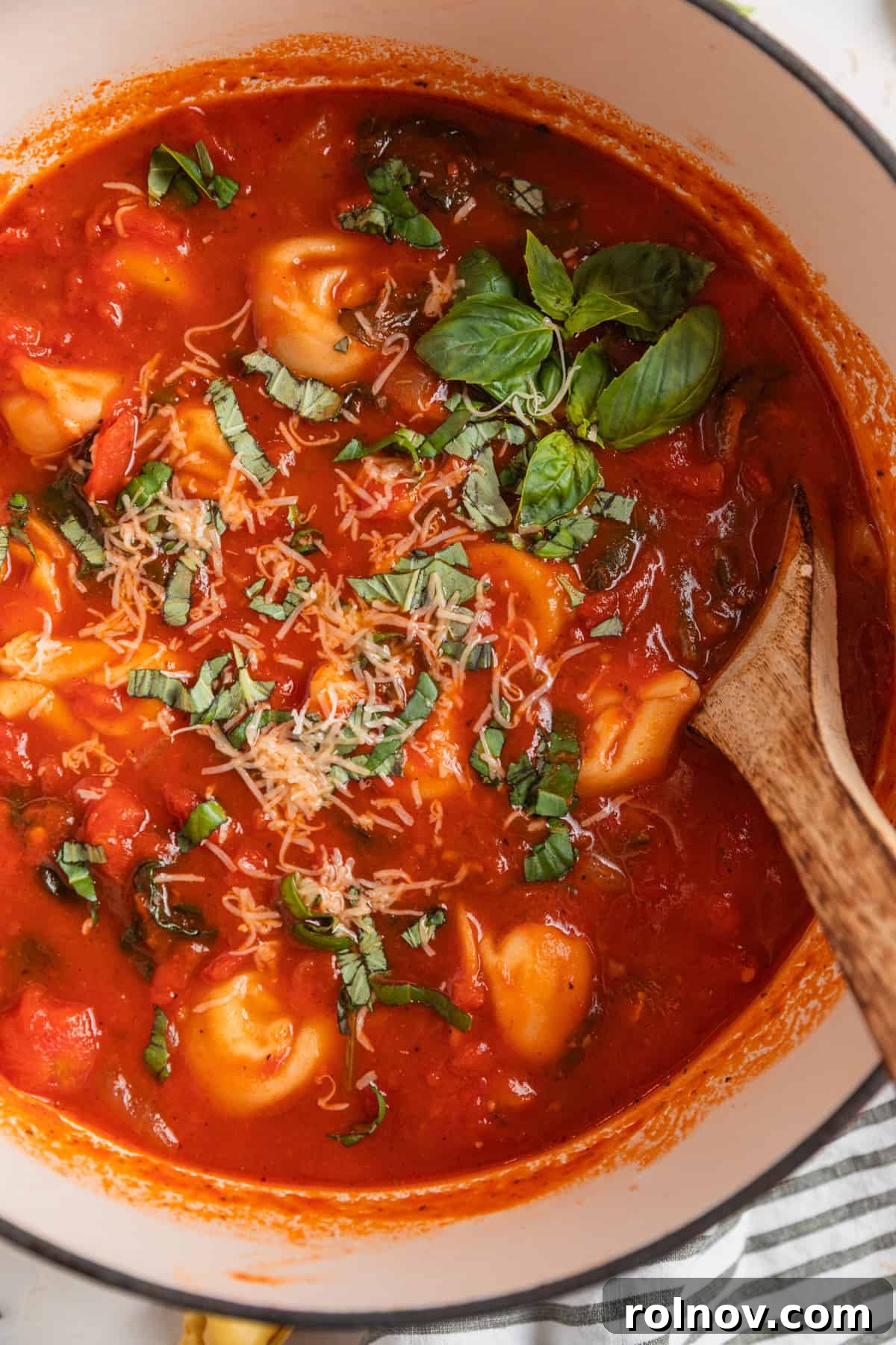 Velvety Tomato Tortellini Soup 6 Dutch oven with tomato tortellini soup and wooden spoon scooping in.
