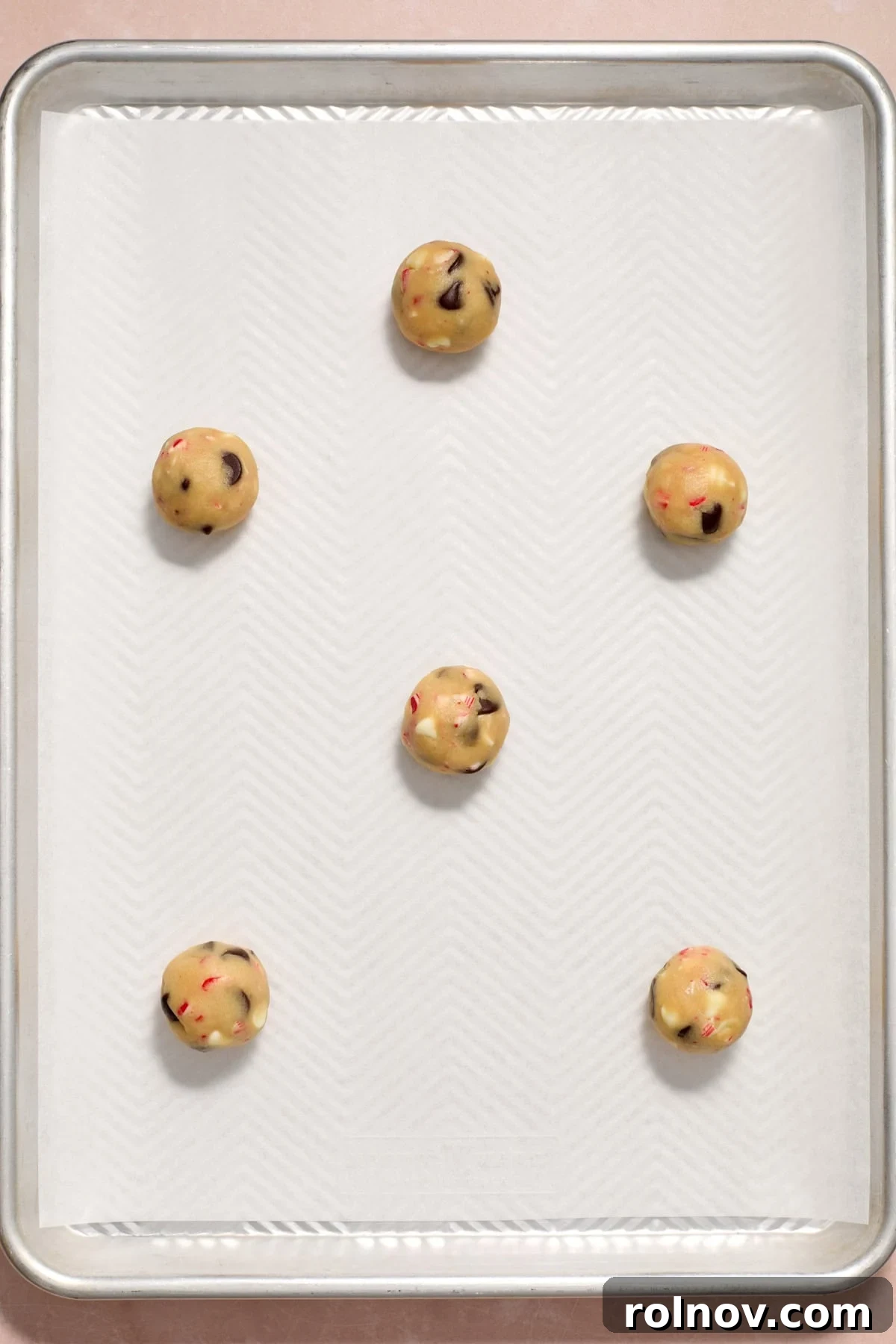 Cool Peppermint Chocolate Chip Cookies 13 Rolled cookie dough balls neatly arranged on a parchment-lined baking sheet, spaced for even baking.
