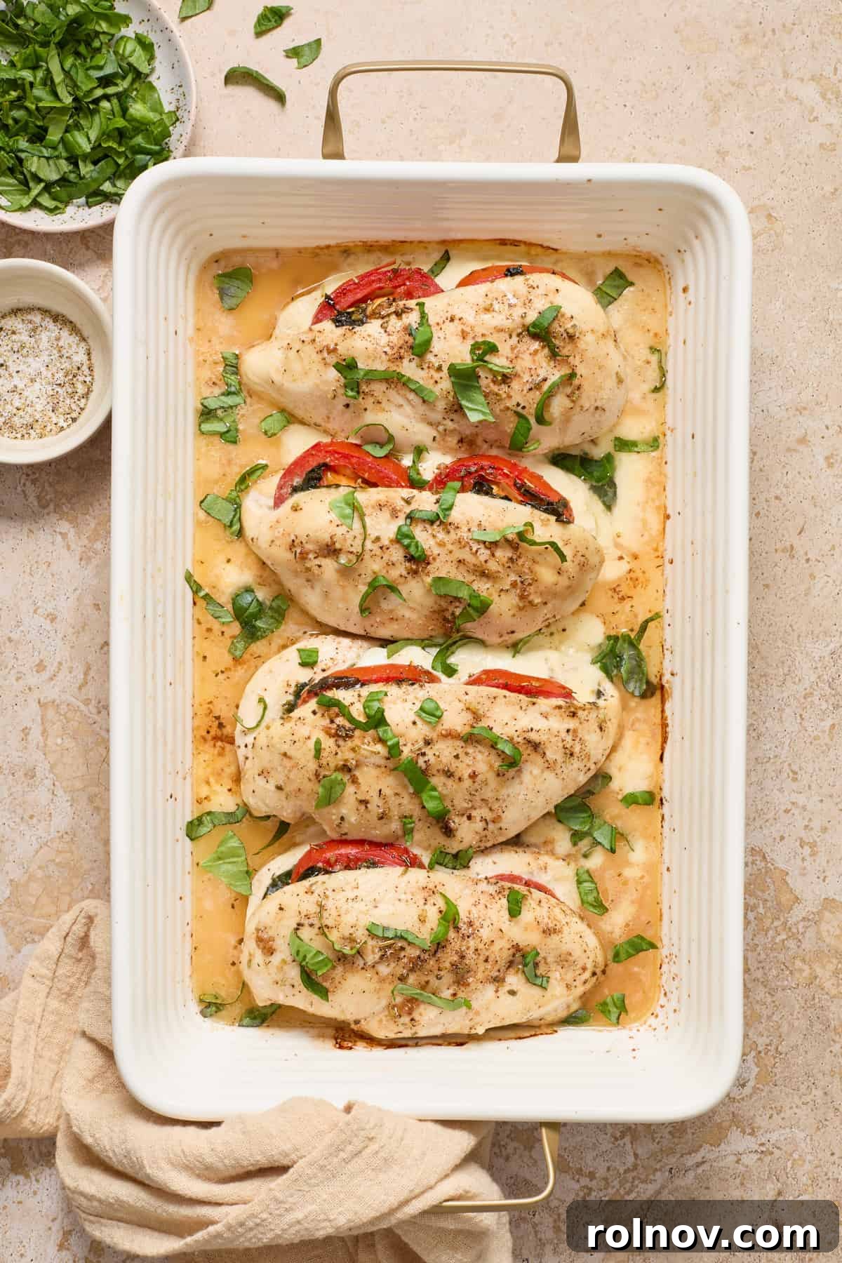 Cooked mozzarella stuffed chicken with chopped basil on top, served with a fresh salad.