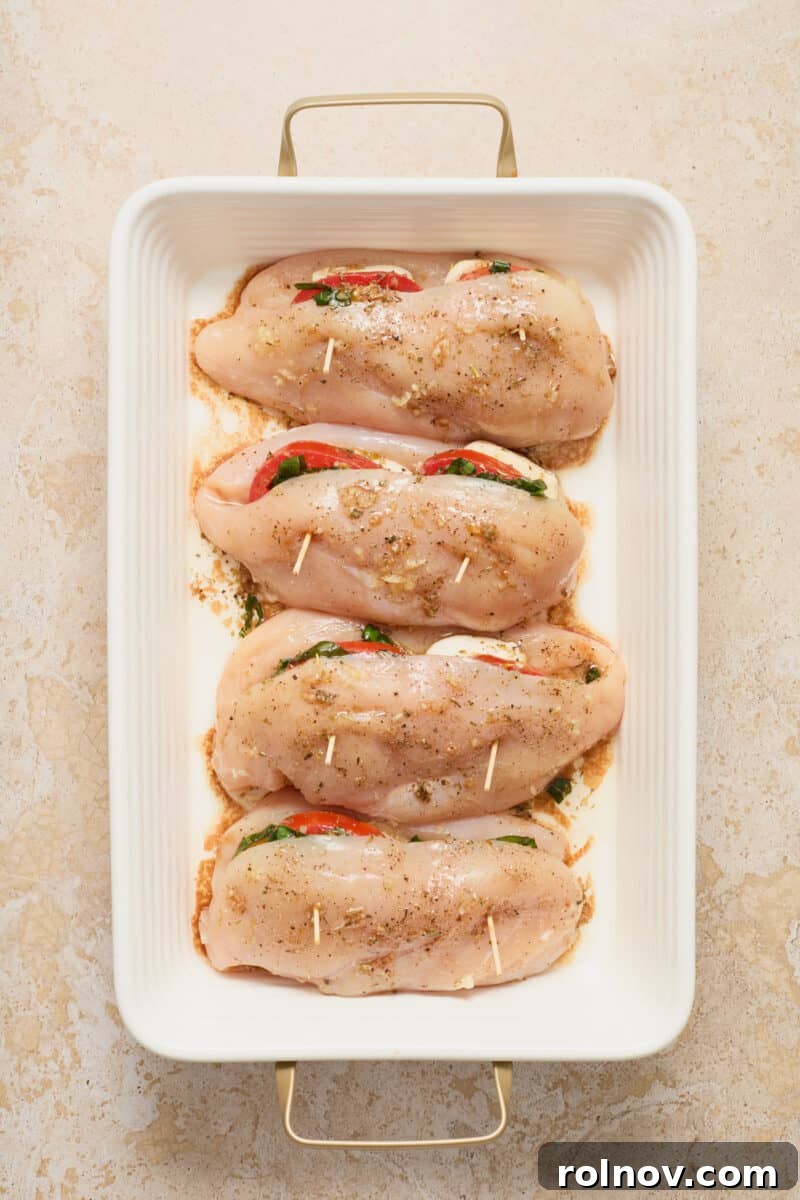 Baking dish with prepared mozzarella, tomato, and basil stuffed chicken breasts before baking.