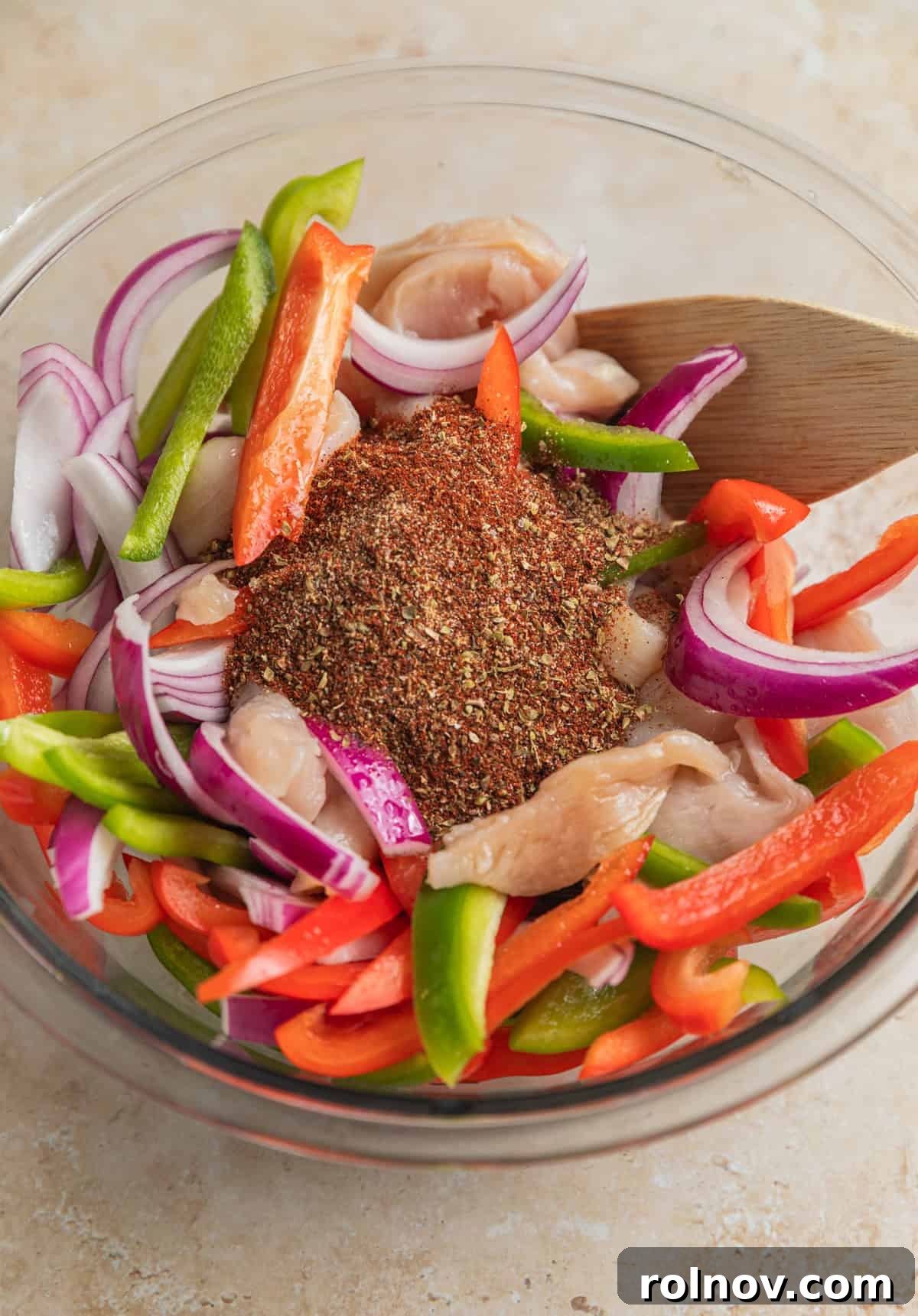 Fajita seasoning and marinade ingredients added to bowl with chicken and veggies.