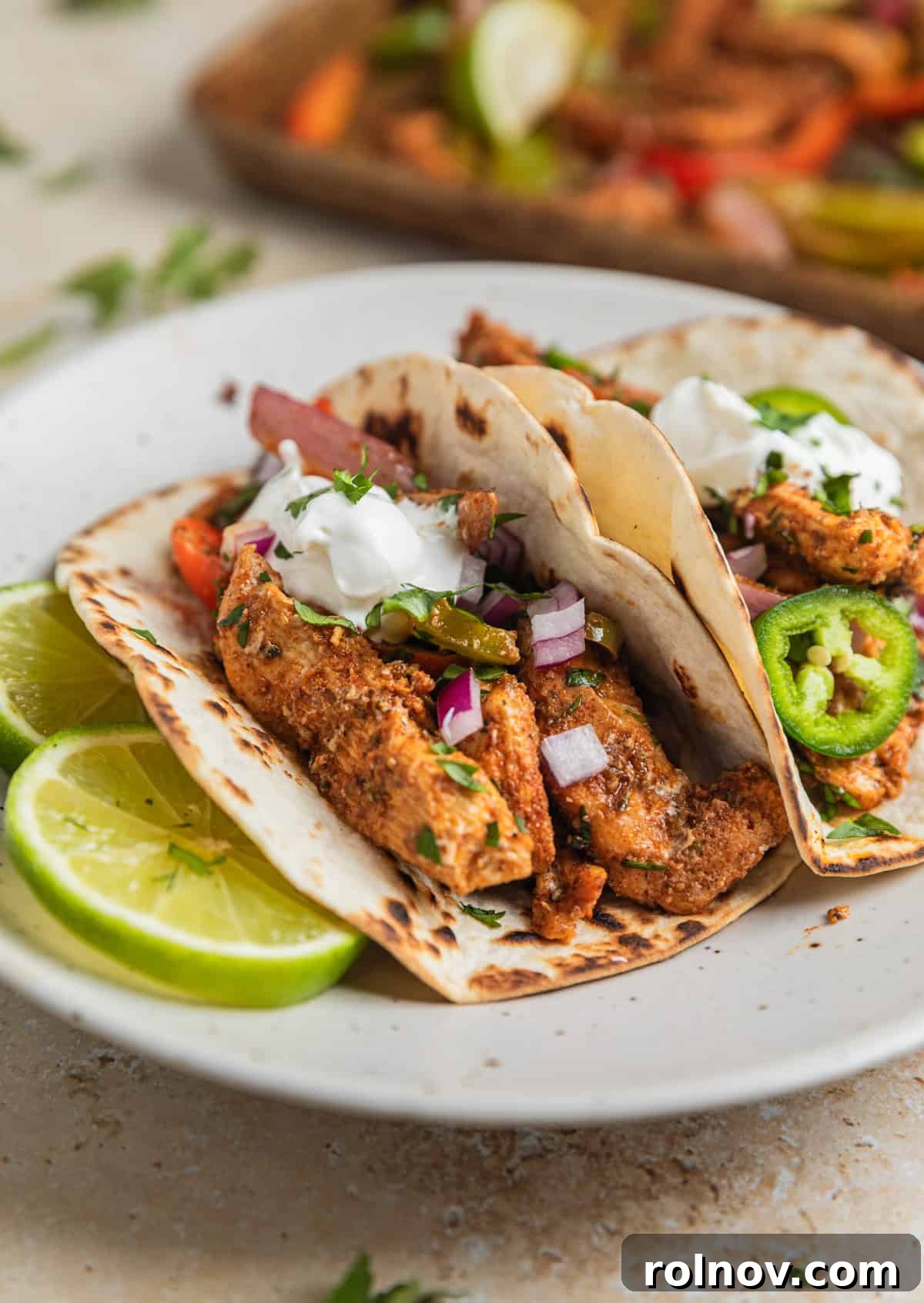 Honey lime chicken fajitas on tortillas on plate with sour cream dollop on top.