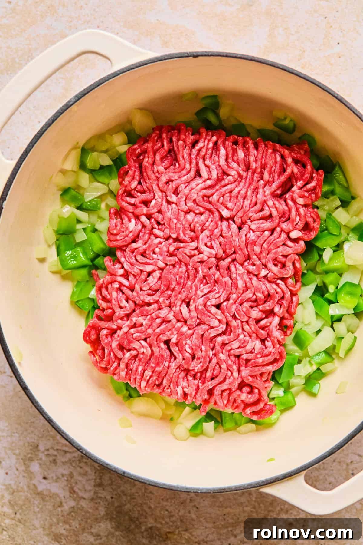 Hearty Skillet Chili Mac 6 One pound of raw ground beef being added to the pot alongside the sautéed onions and bell peppers.
