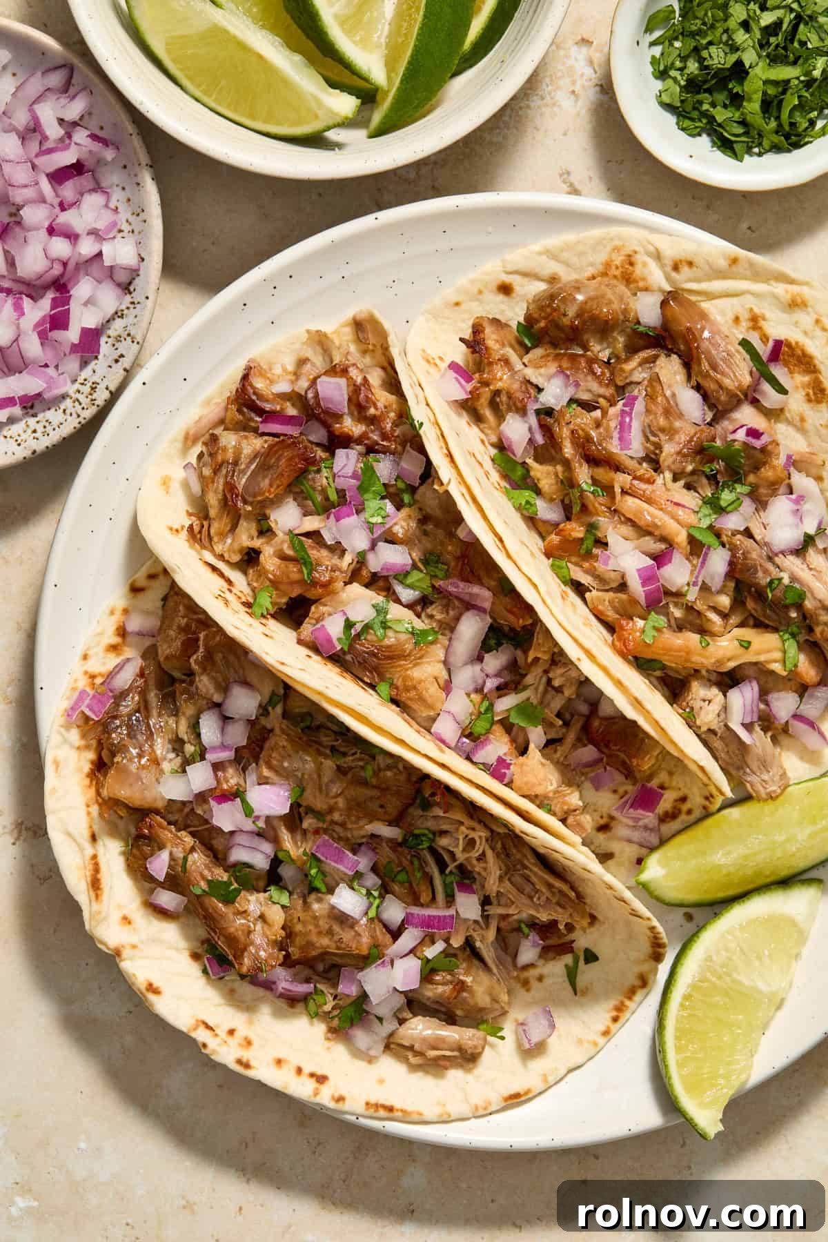 Lightning-Fast Crispy Instant Pot Carnitas 2 Pork carnitas in tortillas topped with diced red onion and chopped cilantro.