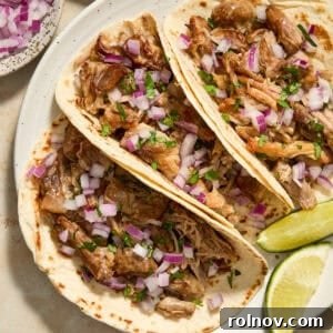 Instant Pot carnitas in tortillas with onion and cilantro on white dish.