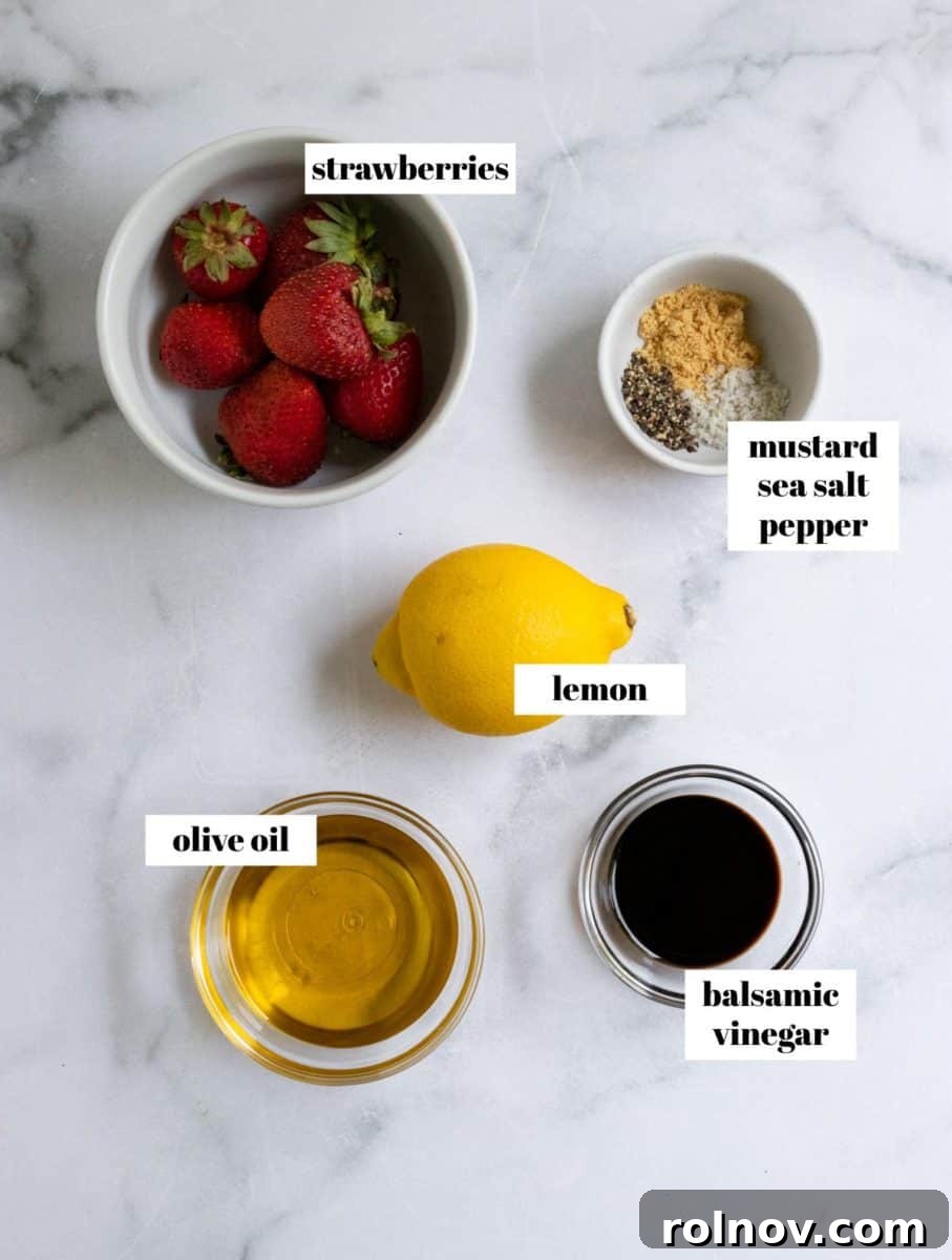 Strawberry Balsamic Berry Salad 4 Individual ingredients for strawberry balsamic dressing, labeled on a white counter, including fresh strawberries, a lemon, balsamic vinegar, olive oil, ground mustard, and cracked pepper.
