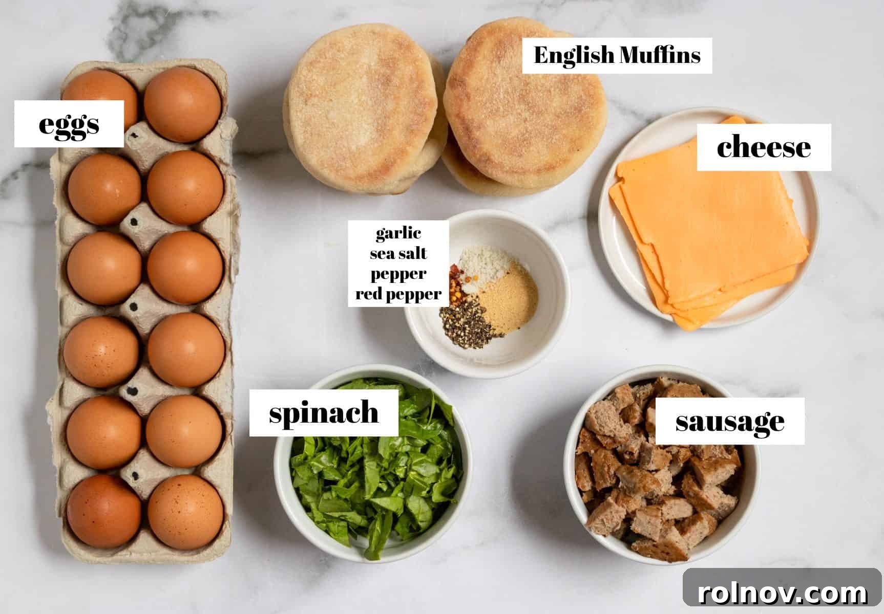 A selection of fresh ingredients including eggs, spinach, sausage, and seasonings laid out on a kitchen counter.