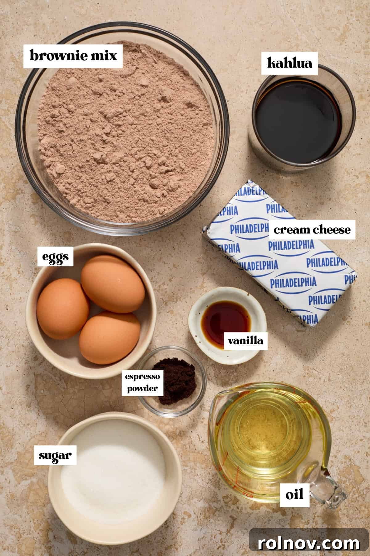 Kahlua Swirled Cream Cheese Brownie Bliss 3 Essential ingredients for Kahlua cheesecake brownies laid out on a surface, including brownie mix, oil, eggs, Kahlua, espresso powder, cream cheese, sugar, and vanilla.