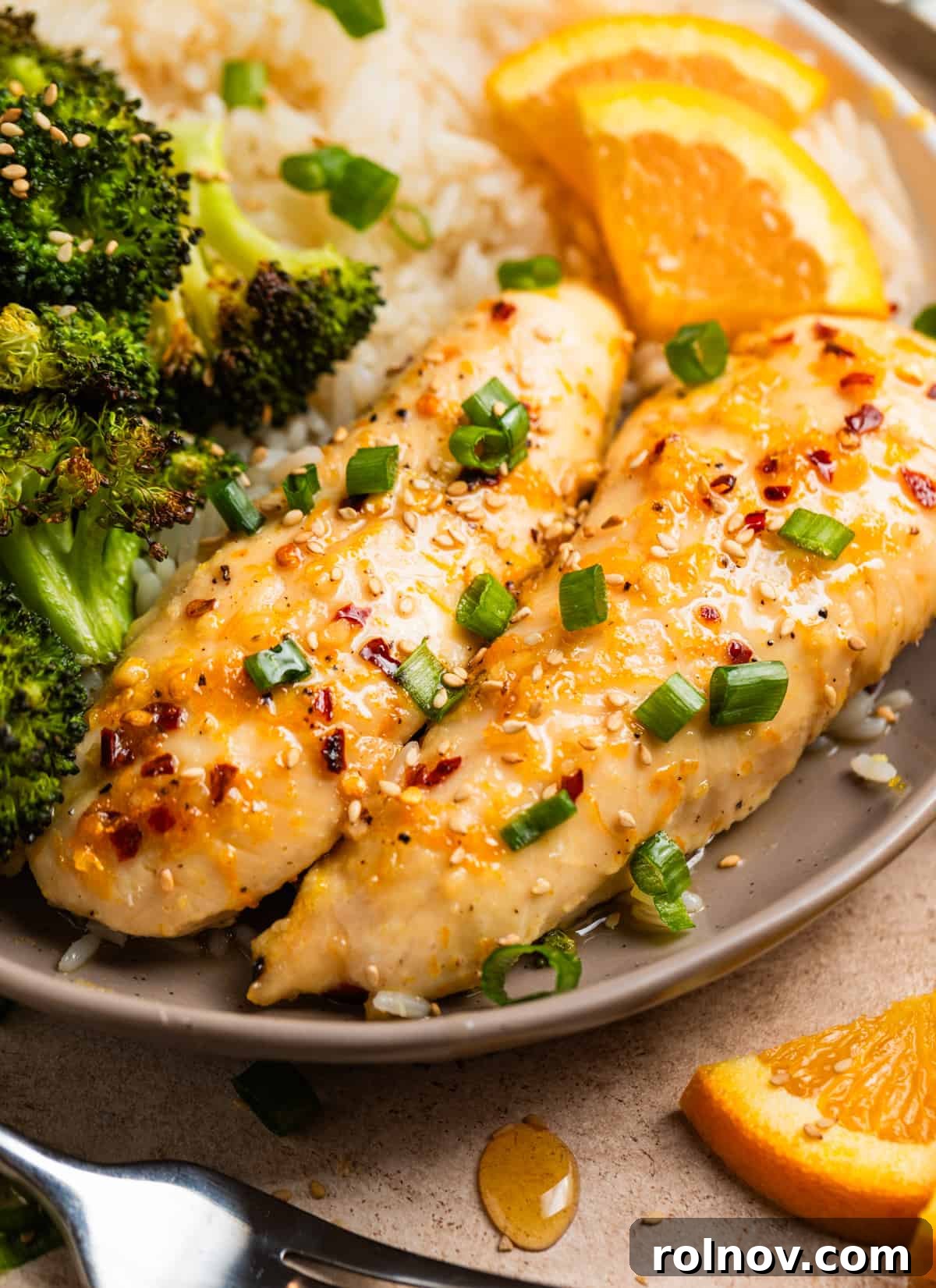 Sticky Orange Chicken One-Pan Dinner 2 Dish with baked orange chicken, broccoli and rice topped with sliced green onions and sesame seeds.