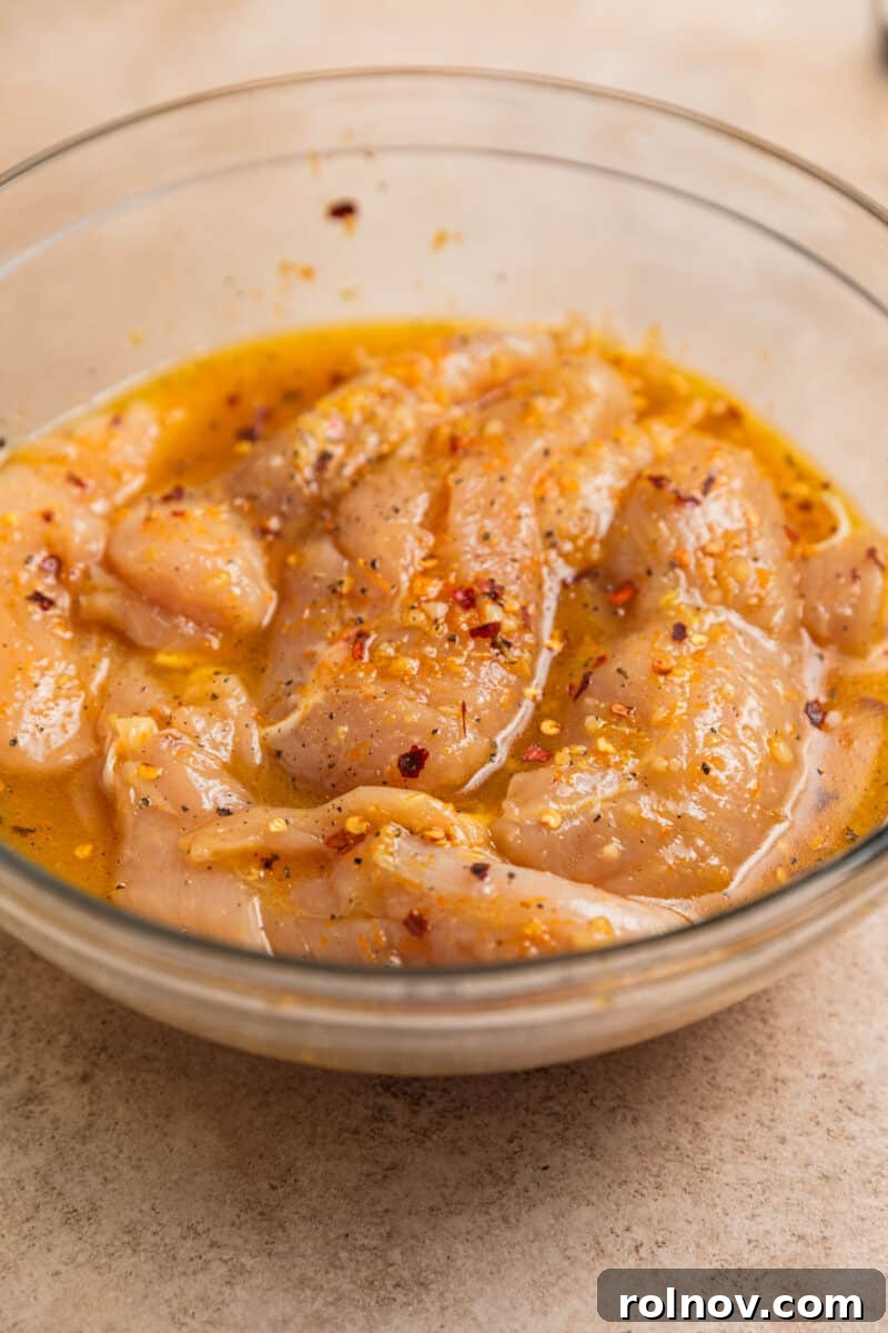 Sticky Orange Chicken One-Pan Dinner 6 Chicken tenderloins marinating in glass bowl with honey orange marinade.