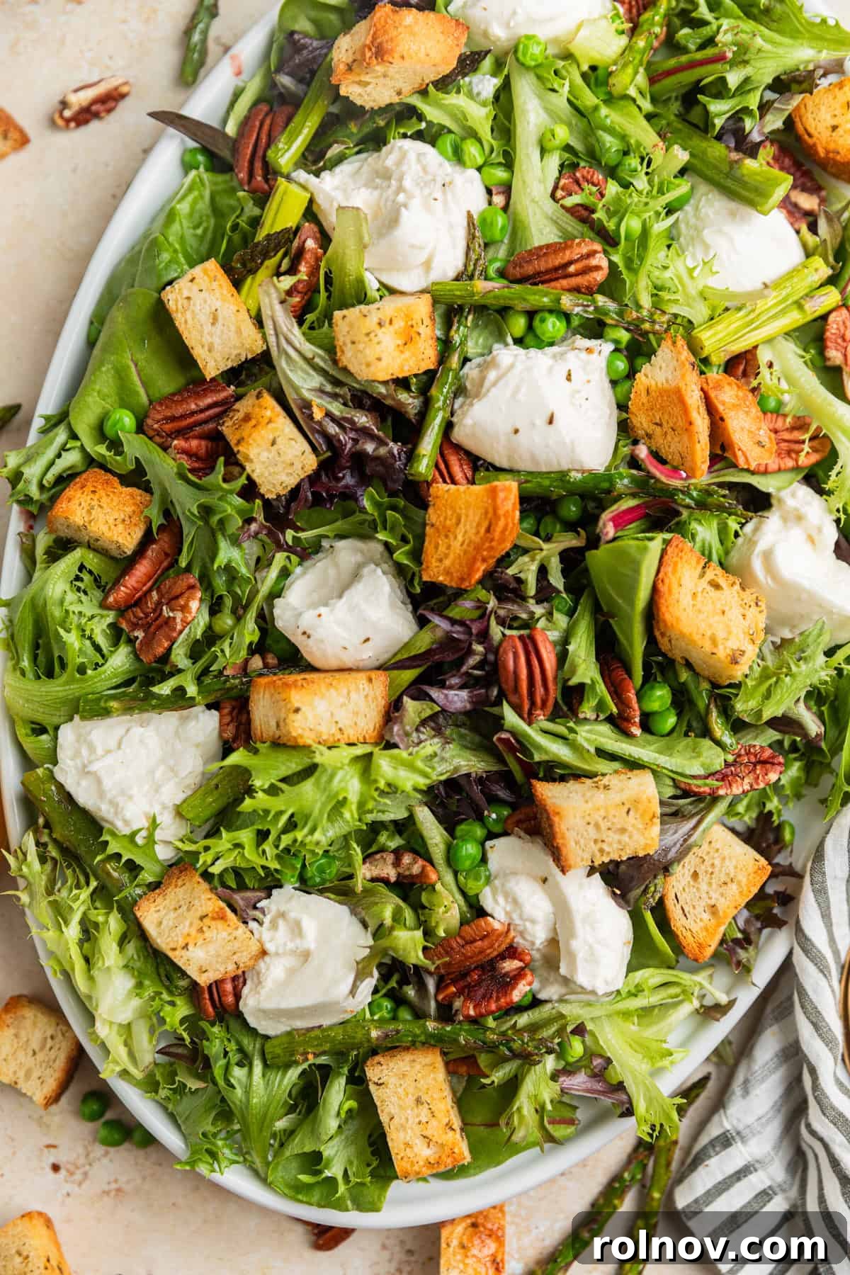 Verdant Burrata Delight 2 Overhead view of a beautiful serving platter showcasing a vibrant spring green and burrata salad, garnished with croutons and a drizzle of dressing.