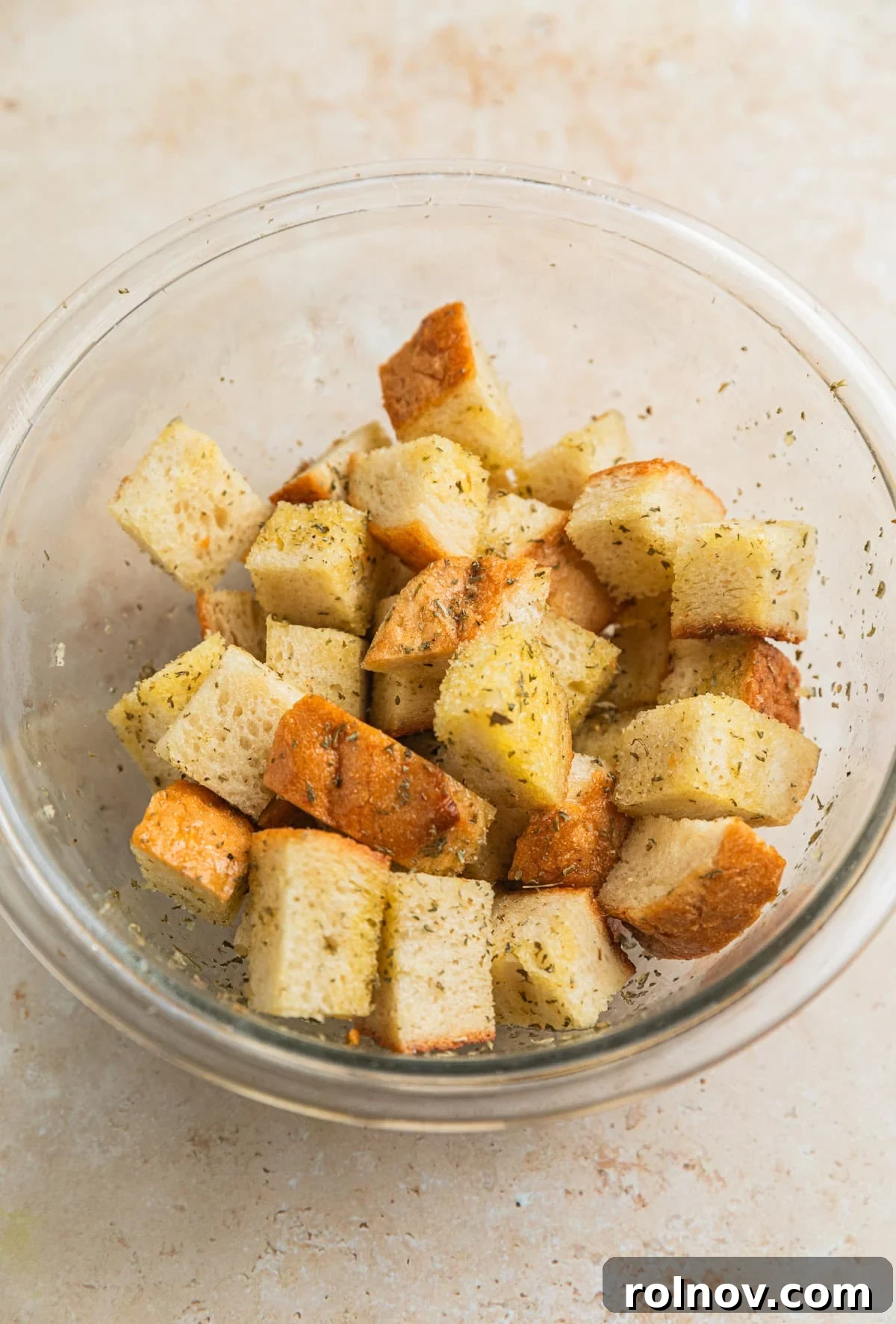 Verdant Burrata Delight 4 Cubed sourdough bread tossed evenly with olive oil and a blend of seasonings in a bowl, ready for baking.