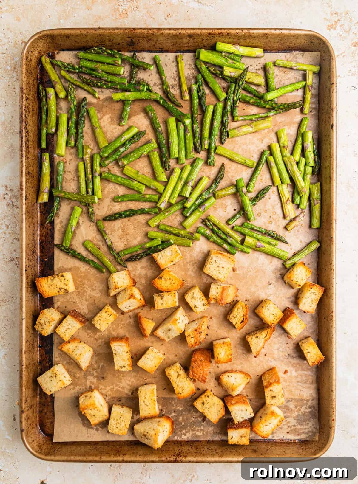Verdant Burrata Delight 6 A sheet pan lined with parchment paper, holding freshly baked golden sourdough croutons and perfectly roasted asparagus, cooling after being removed from the oven.