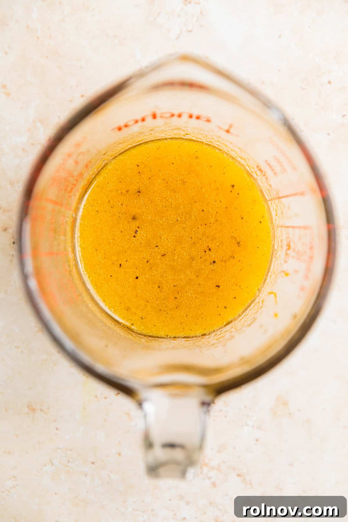 Verdant Burrata Delight 7 A measuring glass cup filled with a beautifully emulsified honey citrus dressing, ready to be drizzled over a fresh salad.