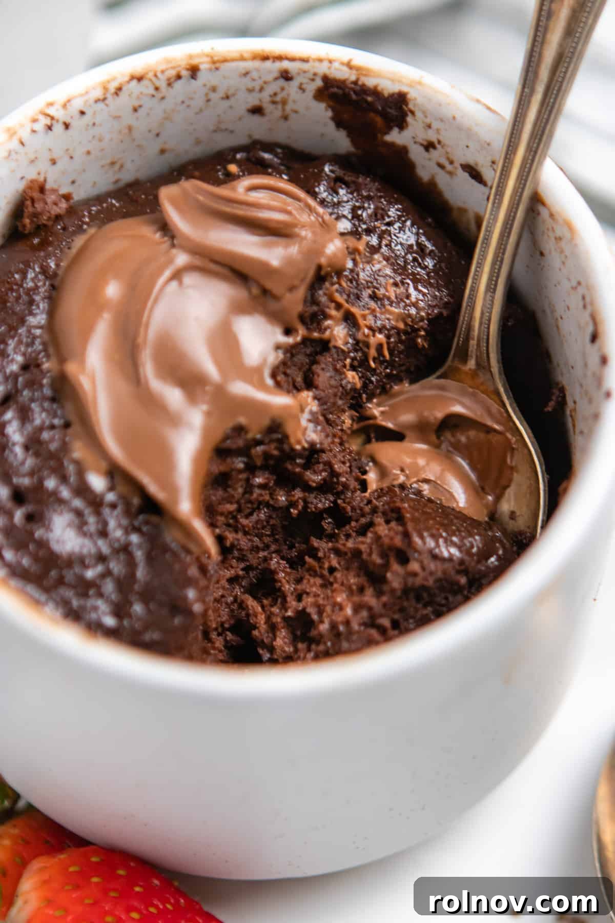 5-Minute Nutella Mug Cake 5 Flourless Nutella mug cake in mug with dollop of Nutella on top and a spoon, ready to be enjoyed.