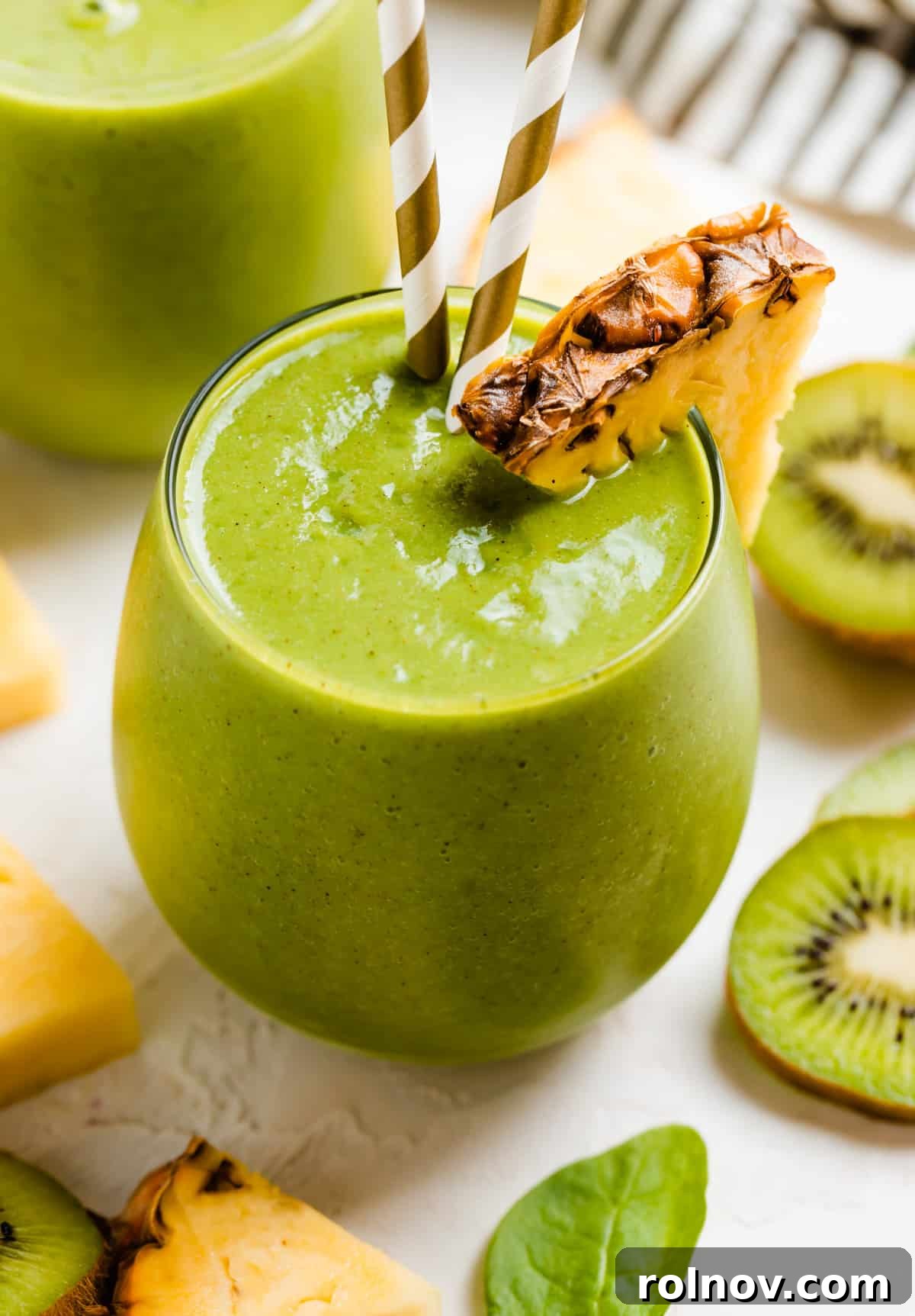 Zesty Green Kiwi Pineapple Boost 2 Pineapple kiwi smoothie in glass with pineapple and kiwi slices.