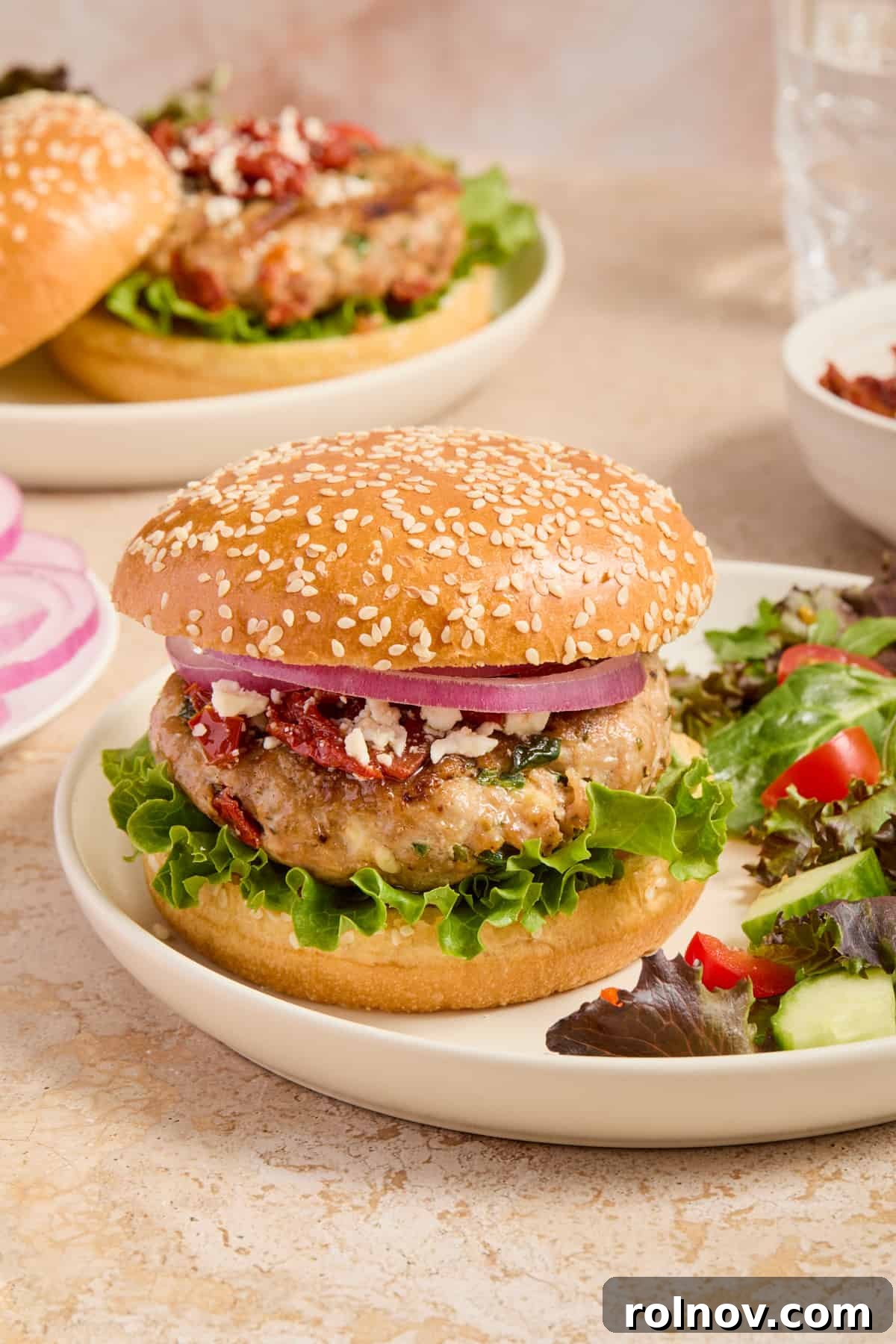 Spinach and feta turkey burger on hamburger bun with lettuce, onion, feta crumbles and sun-dried tomatoes.